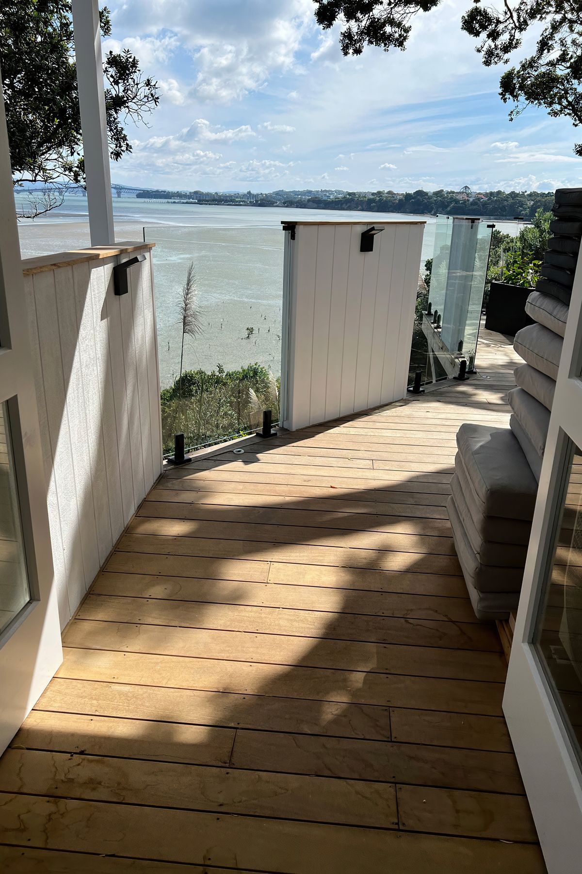 Wooden deck with a mixture of white painted wood and glass barriers overlooking the sea