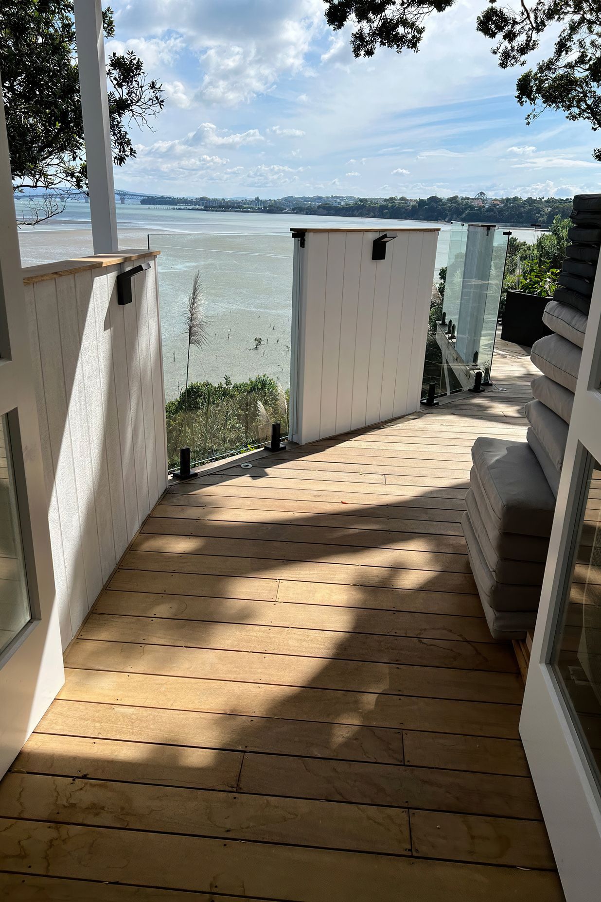Wooden deck with a mixture of white painted wood and glass barriers overlooking the sea