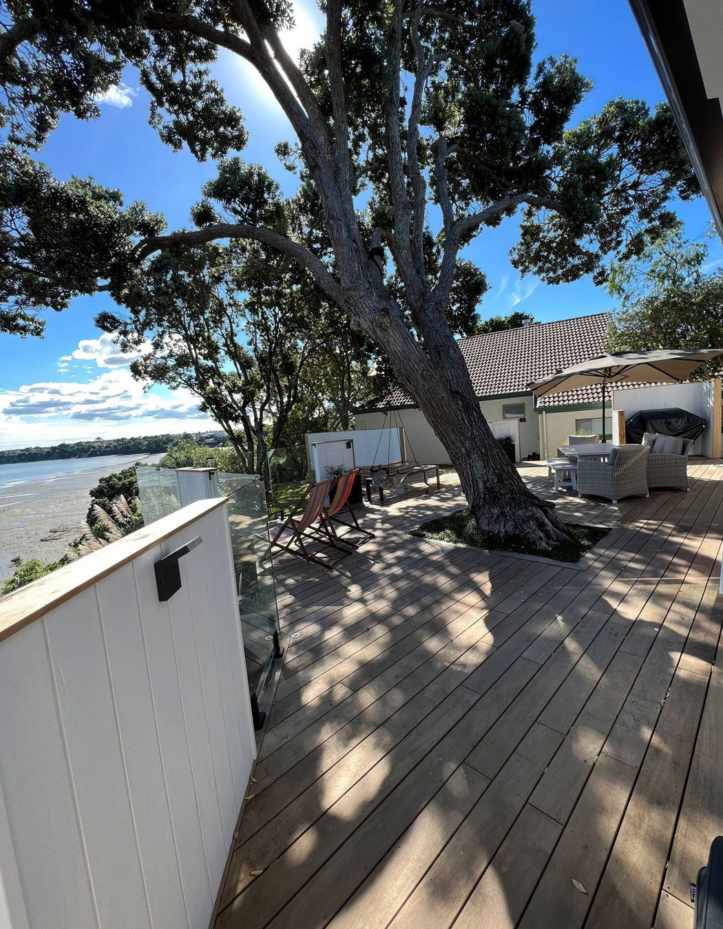 Large outdoor deck area built around a large tree with plenty of shade and outdoor furniture