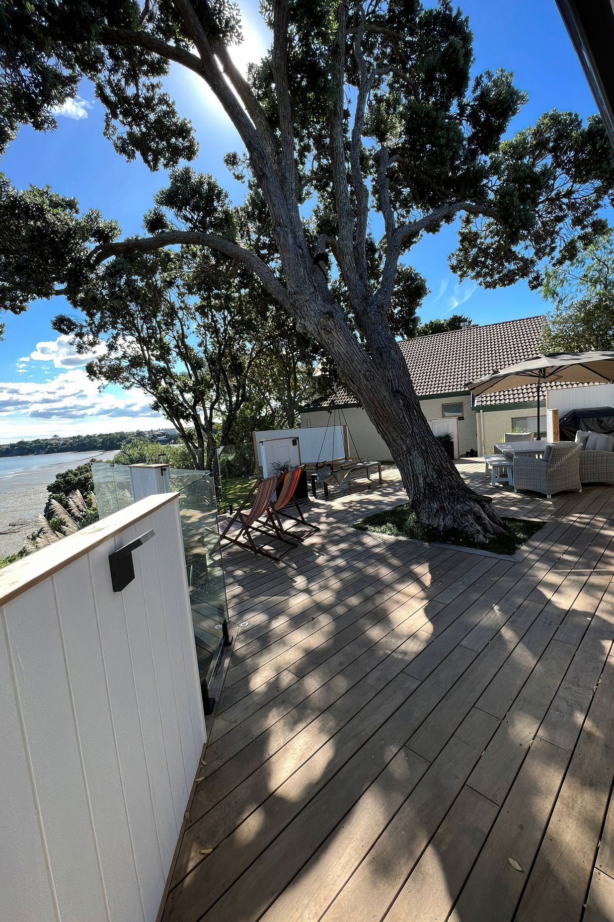 Large outdoor deck area built around a large tree with plenty of shade and outdoor furniture
