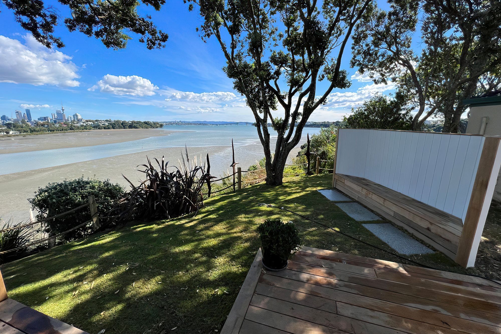 Auckland backyard cordoned off by a wooden rope fence, with a wooden bench and a big tree casting shade