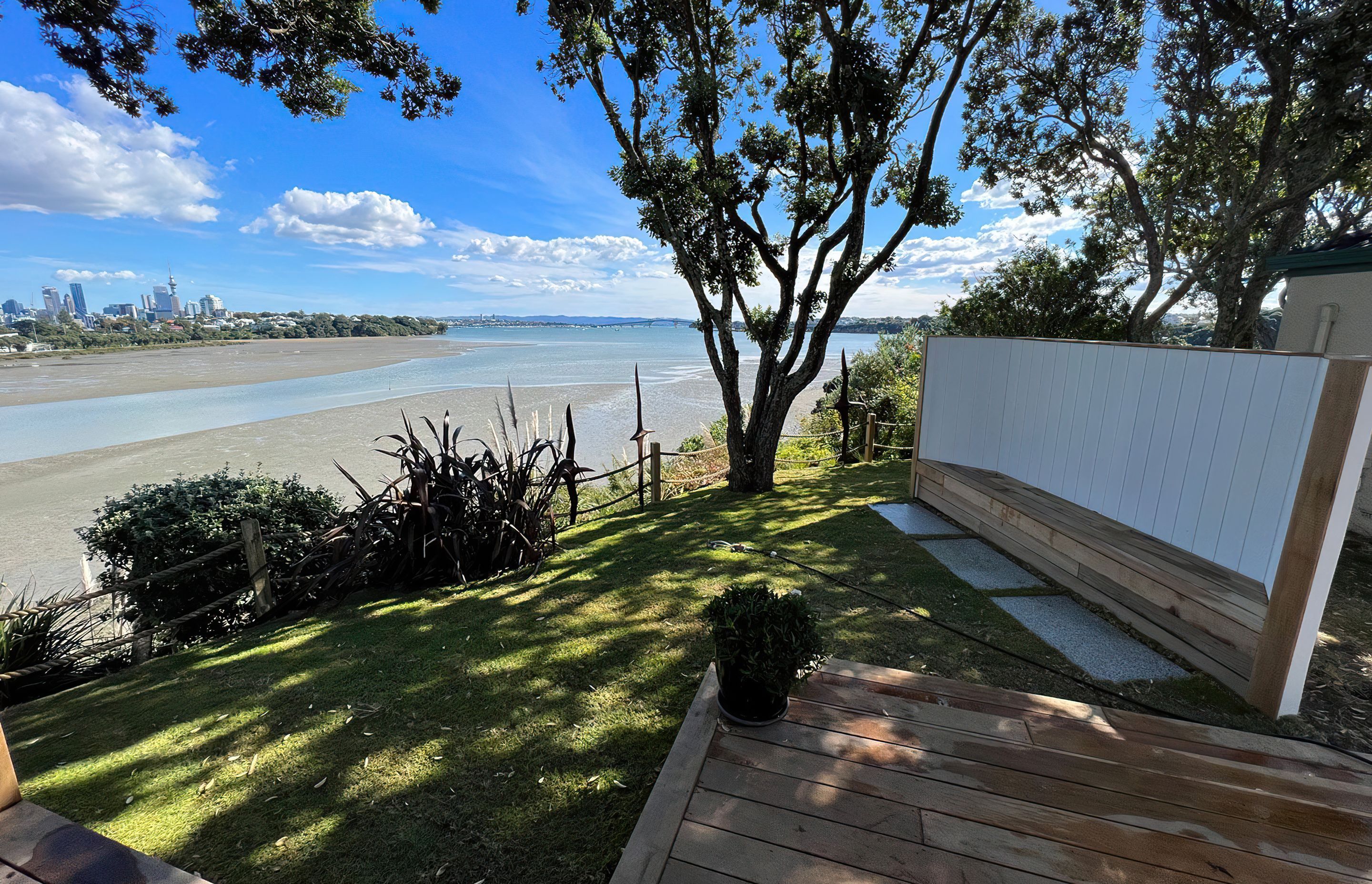 Auckland backyard cordoned off by a wooden rope fence, with a wooden bench and a big tree casting shade