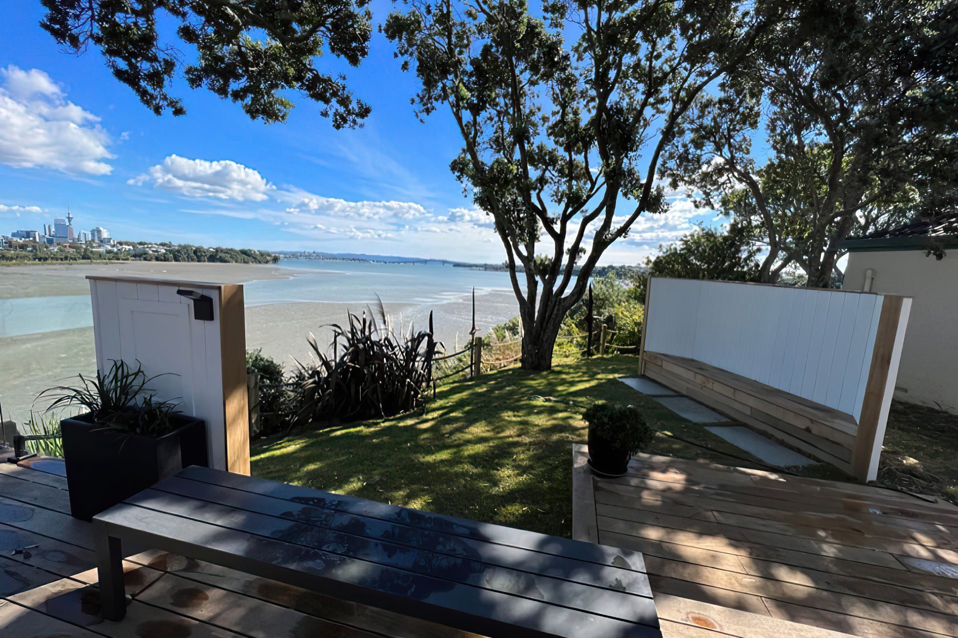 Auckland backyard cordoned off by a wooden rope fence, with a wooden bench and a big tree casting shade