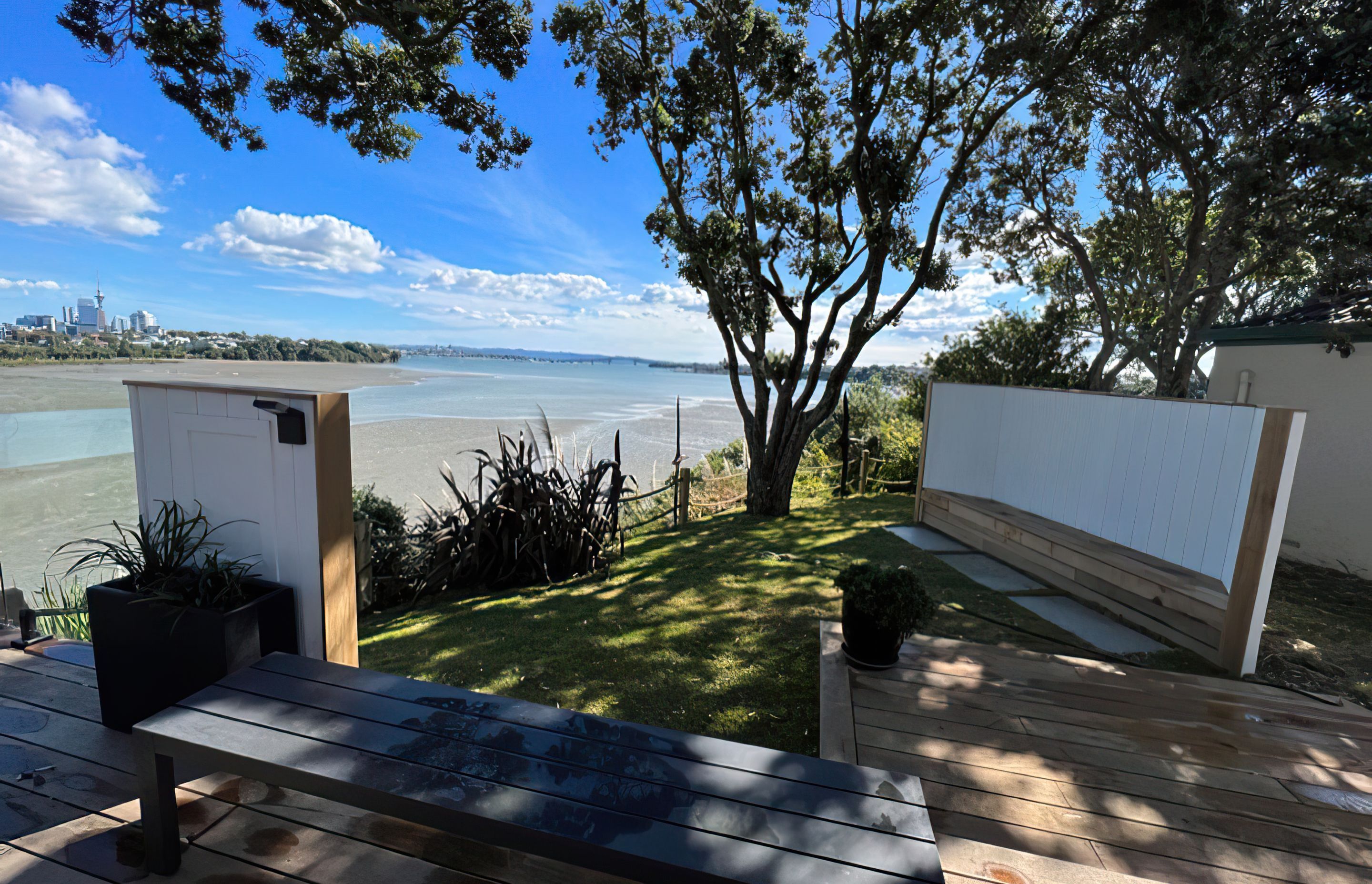 Auckland backyard cordoned off by a wooden rope fence, with a wooden bench and a big tree casting shade