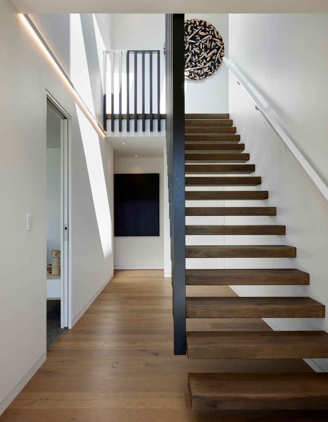 Floating timber stairs lead up to the second level.