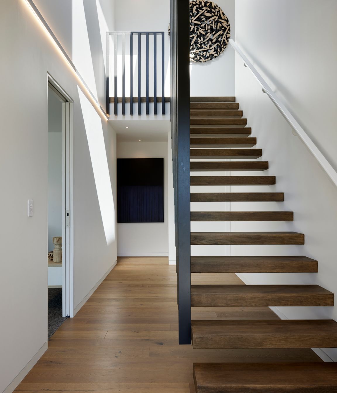 Floating timber stairs lead up to the second level.