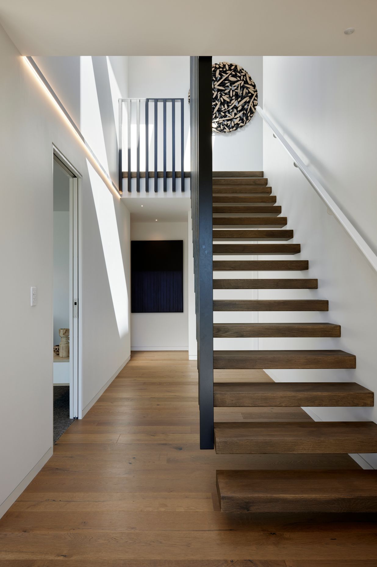 Floating timber stairs lead up to the second level.