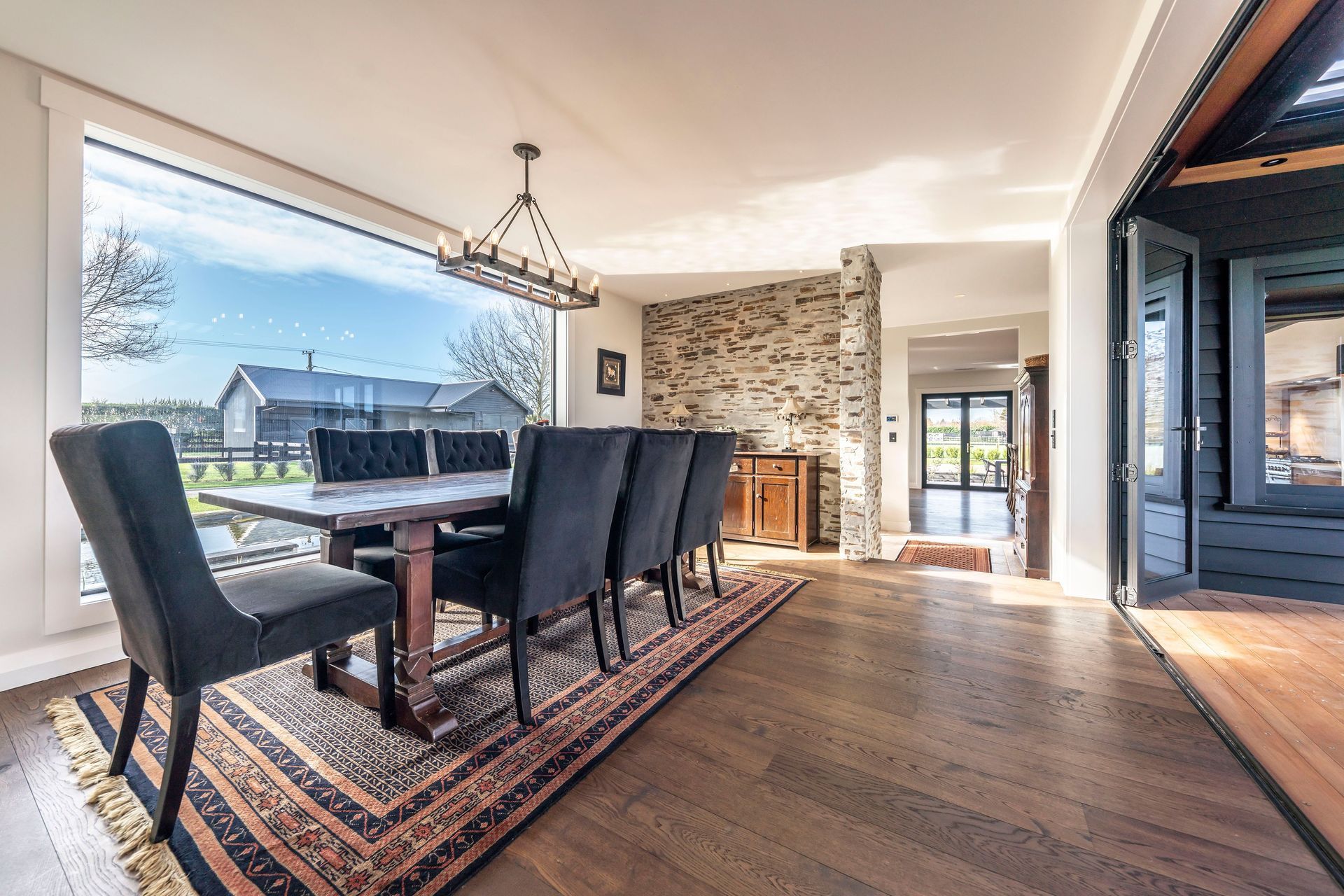 The formal dining area enjoys an elevated position with views over the pond through the large, plate glass window on one side and access to the external entertaining area on the other.