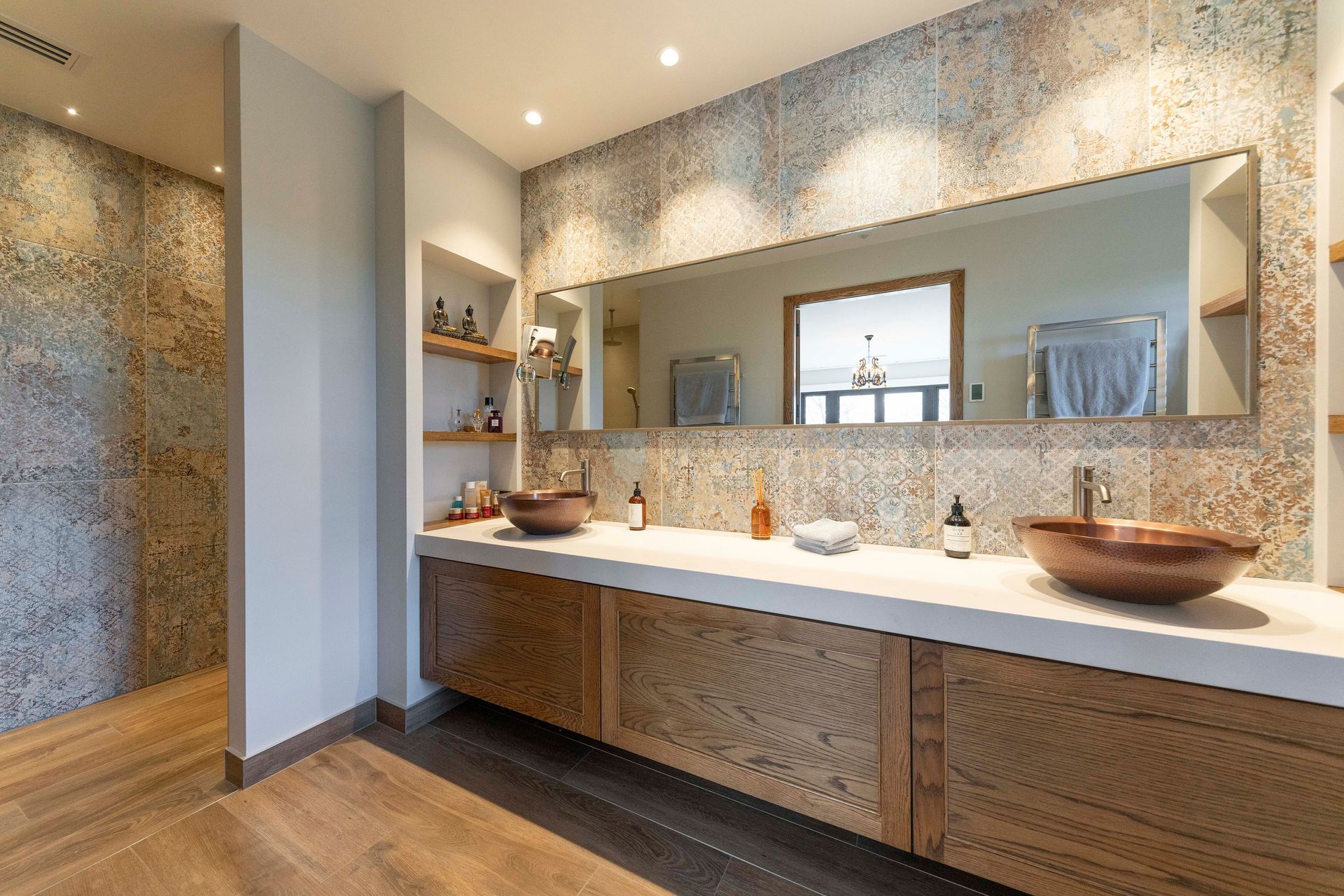 Large-format porcelain tiles, along with timber floors and cabinetry are teamed with copper basins to form a material palette that echoes the exterior materials, exuding a soft yet durable aesthetic.