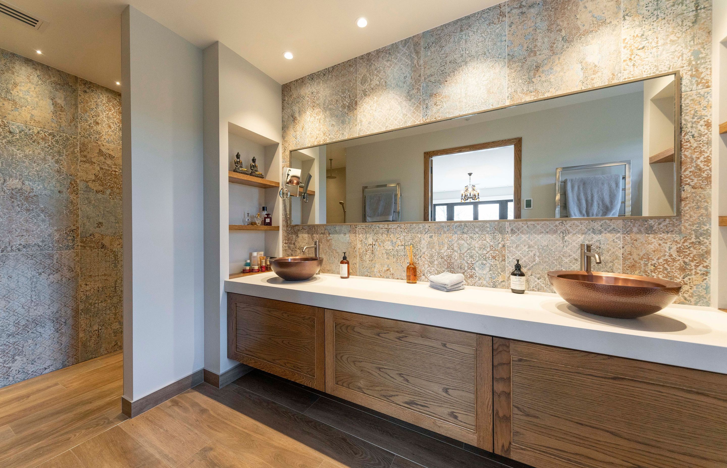 Large-format porcelain tiles, along with timber floors and cabinetry are teamed with copper basins to form a material palette that echoes the exterior materials, exuding a soft yet durable aesthetic.