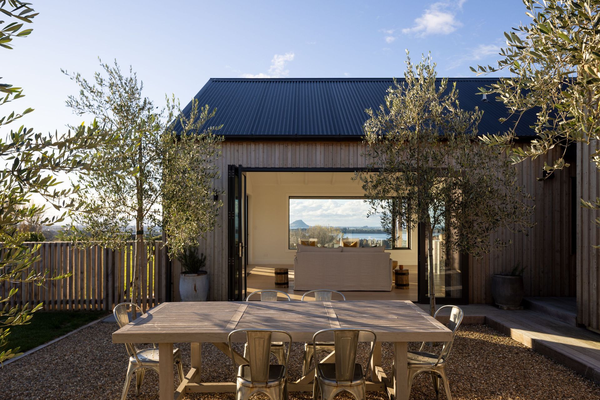 A view from the sheltered courtyard showcases the living room and the stunning view of Mount Maunganui beyond.