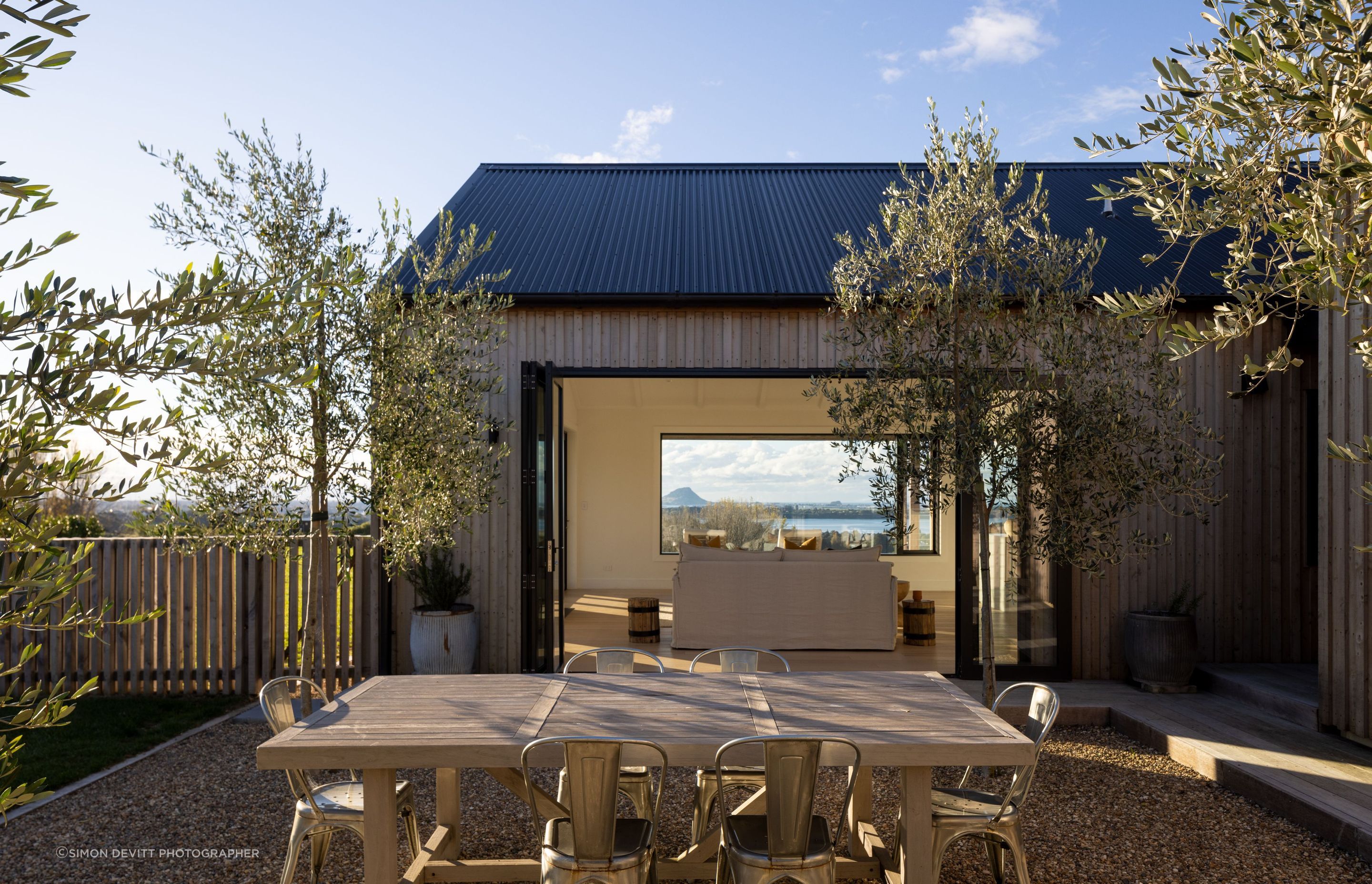 A view from the sheltered courtyard showcases the living room and the stunning view of Mount Maunganui beyond.