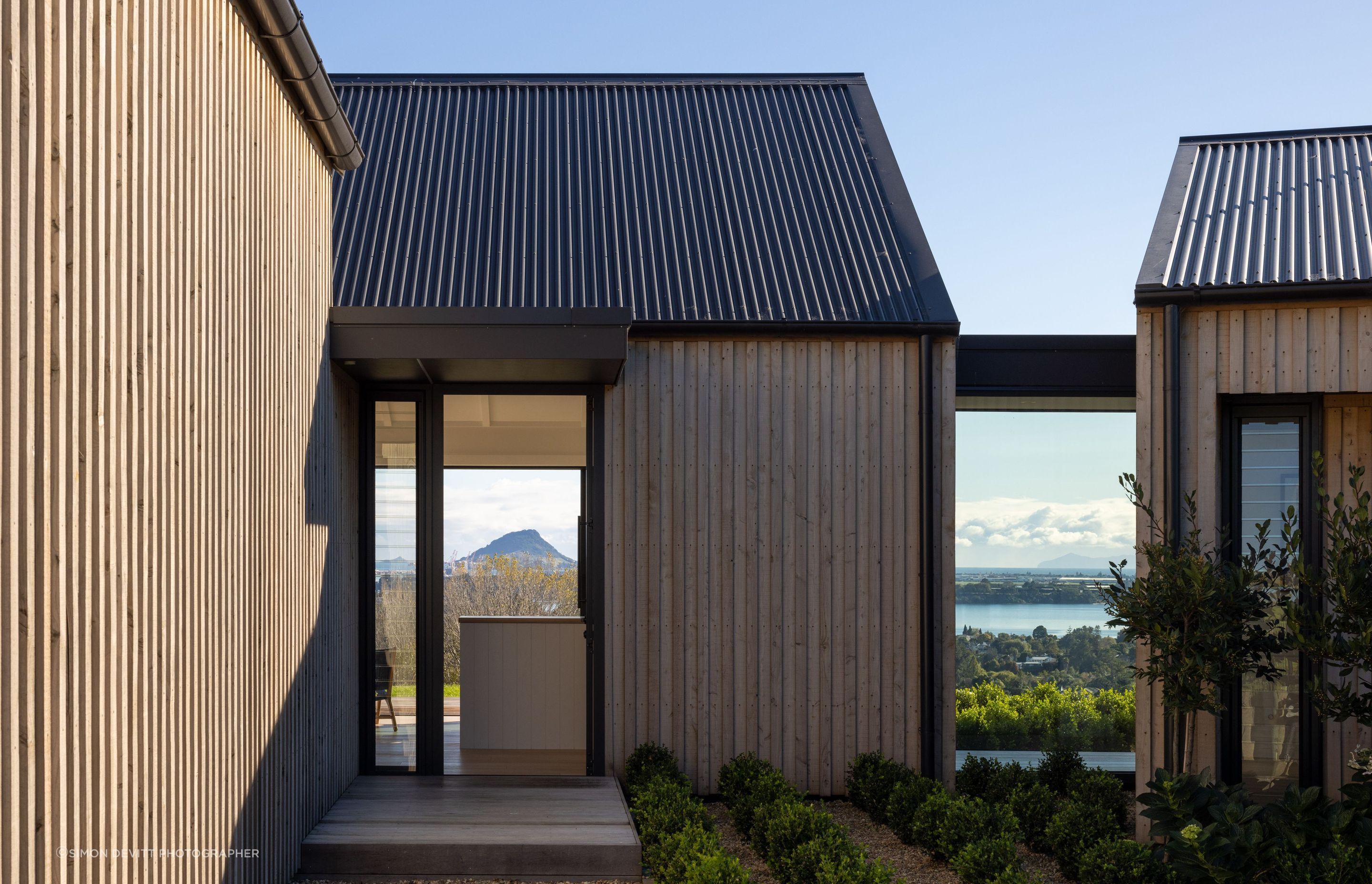 The unostentatious entry is accessed to the right of the garage and leads visitors directly into the living spaces; a glass atrium to the right of the entry enforces separation between  the living and bedroom spaces, while also offering visitors a sneak p