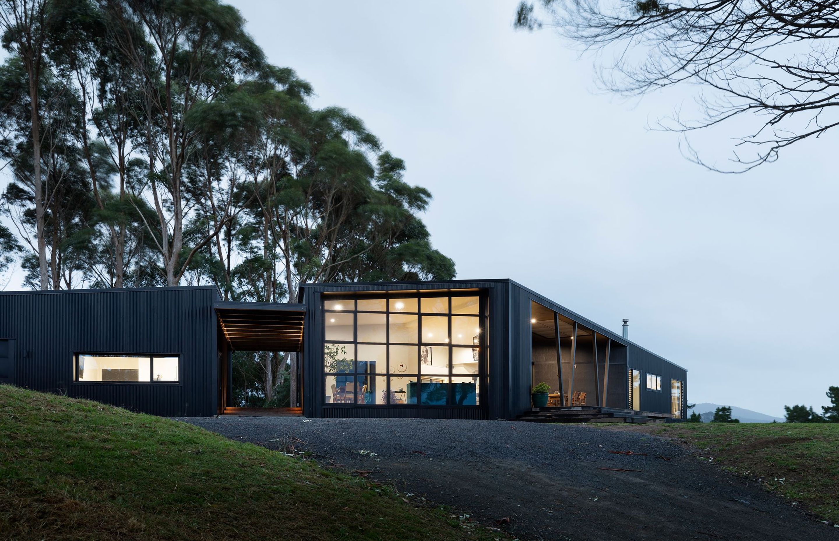 Located on a semi-rural, two-acre block on the west coast of the North Island, this home sits atop a ridgeline and revels in its backdrop of mature eucalypts and an outlook that takes in the west coast mountain ranges and distant ocean view.