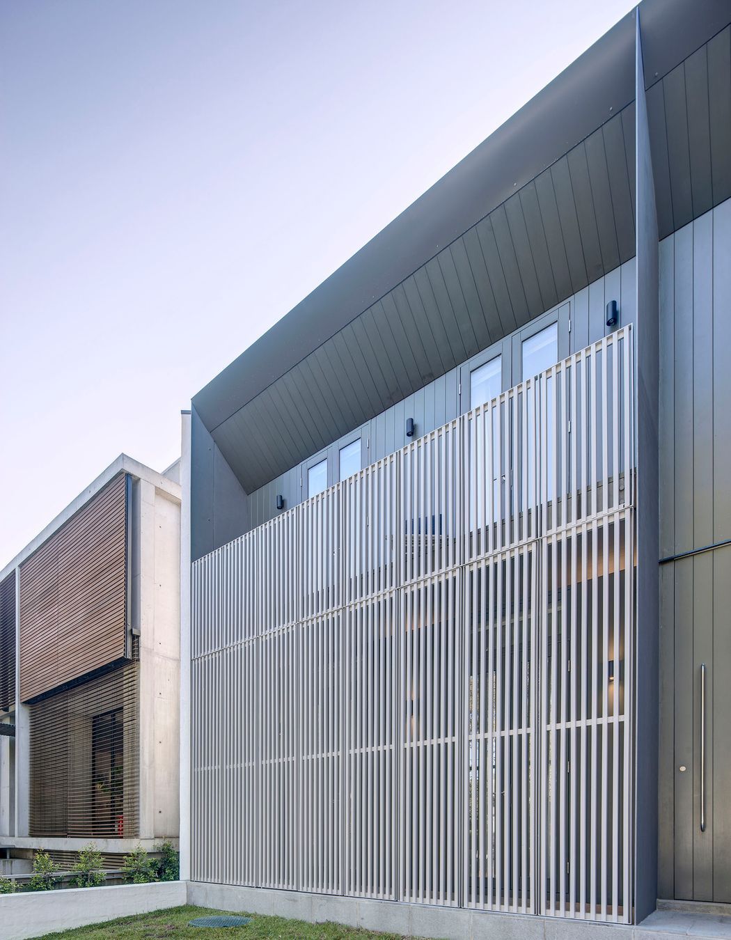 Hinged screens cloak the front elevation, mediating the interface with the street.