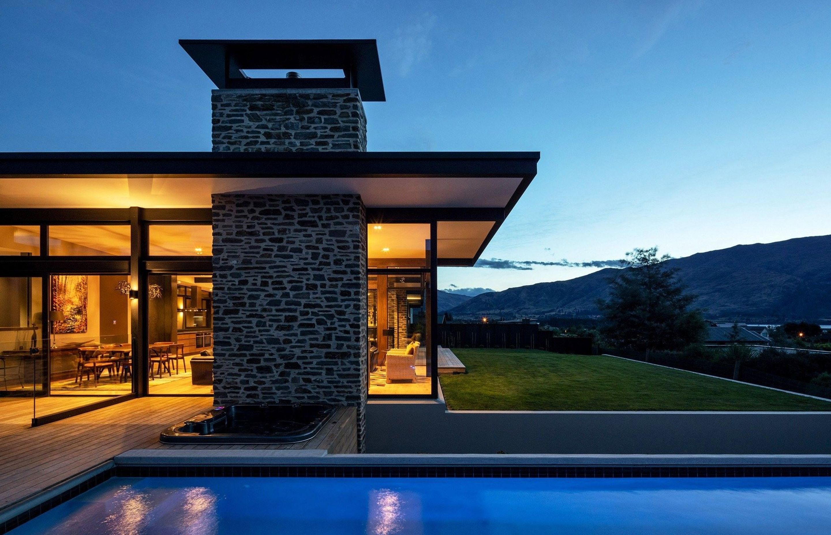 The large, stone-clad chimney elements extend up from the ground and serve to visually anchor the delicate glass facade, as well as further referencing the link to the Otago landscape.