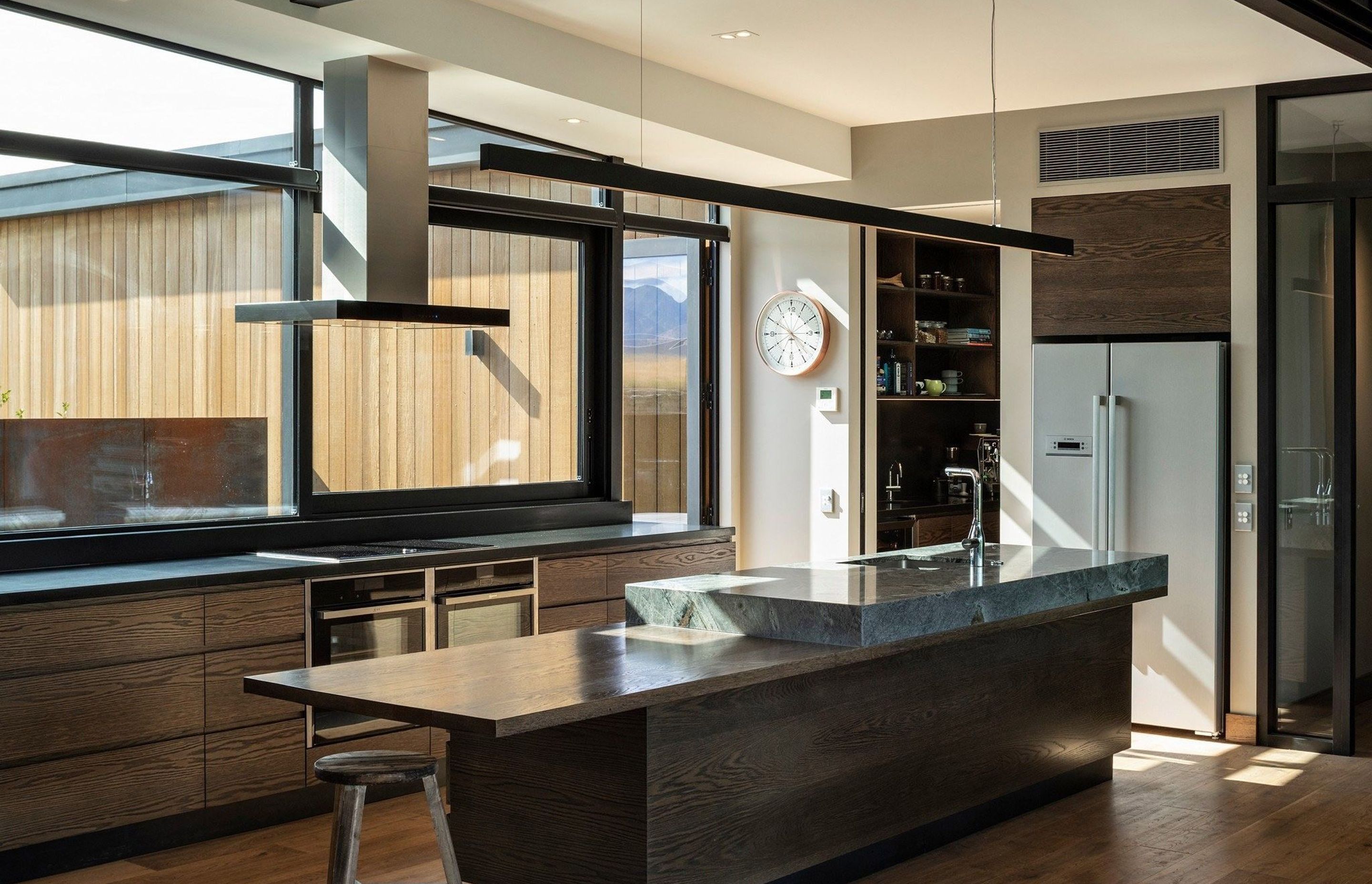 In the kitchen, dark-stained timber cabinetry and floorboards are paired with solid granite benchtops and earthy paint tones to create a warm and comfortable interior that also reflects the strength of the Otago countryside.