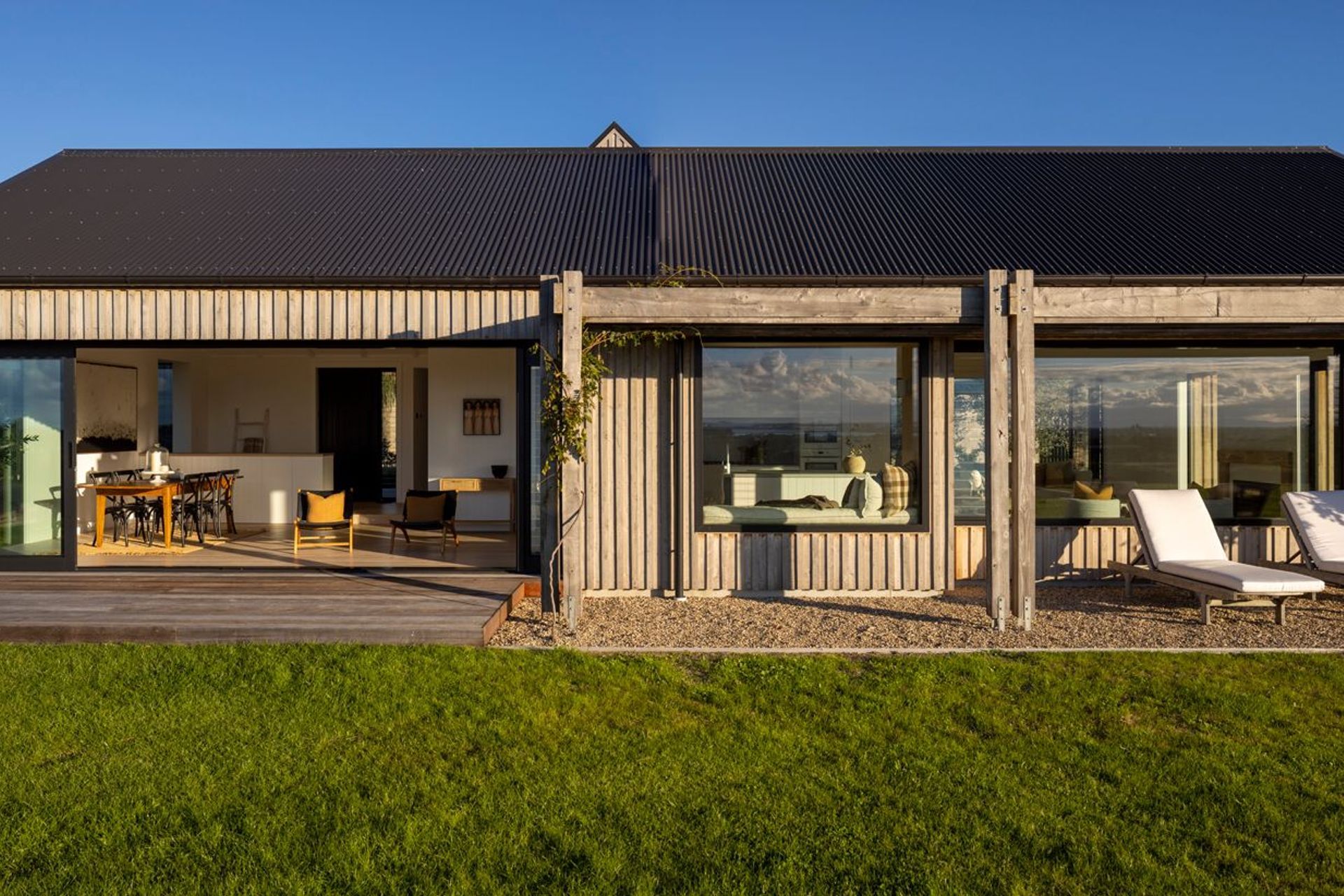 A view of the living spaces from the front lawn; the board and batten cladding is in cypress hardwood, which has a rustic yet refined aesthetic.