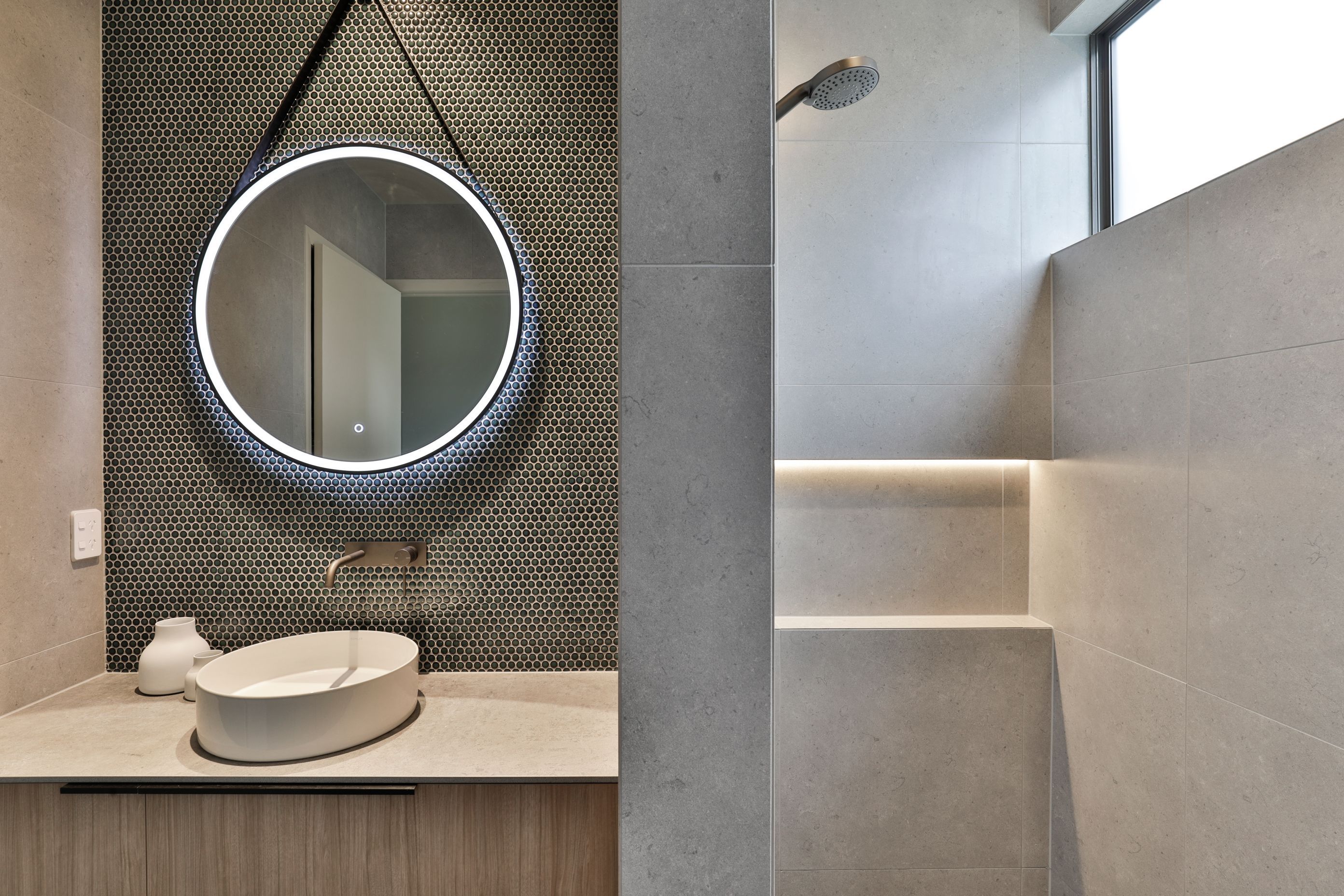 Design by Cube Dentro. Glass-less shower with tiled dividing wall. Cordoba Pearl 600x600mm on the shower and surrounding bathroom walls with Mosaix Penny Round Jade mosaic.