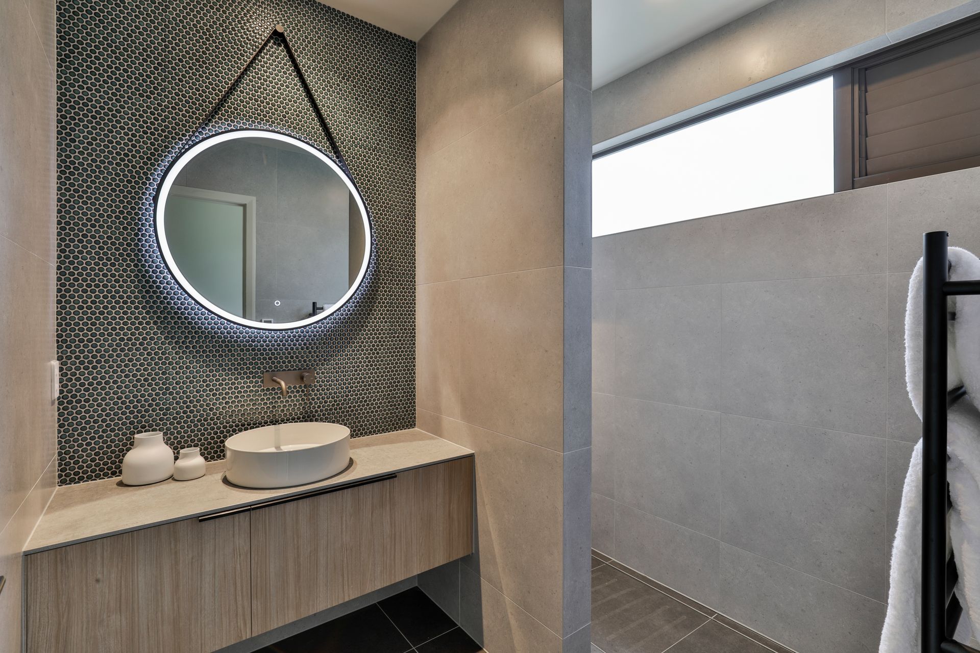 Design by Cube Dentro. Tiles: Cordoba Black 600x600mm on the floor with Cordoba Pearl 600x600mm on the walls. Mosaix Penny Round Jade feature wall behind vanity.