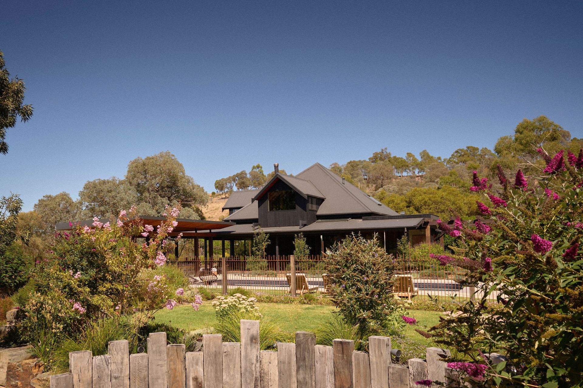 Corrugated iron roofing in Monument by Colorbond. Charred timber cladding from Eco Timber Group. Firepit wall made from recycled grey skin posts from Eco Timber Group.