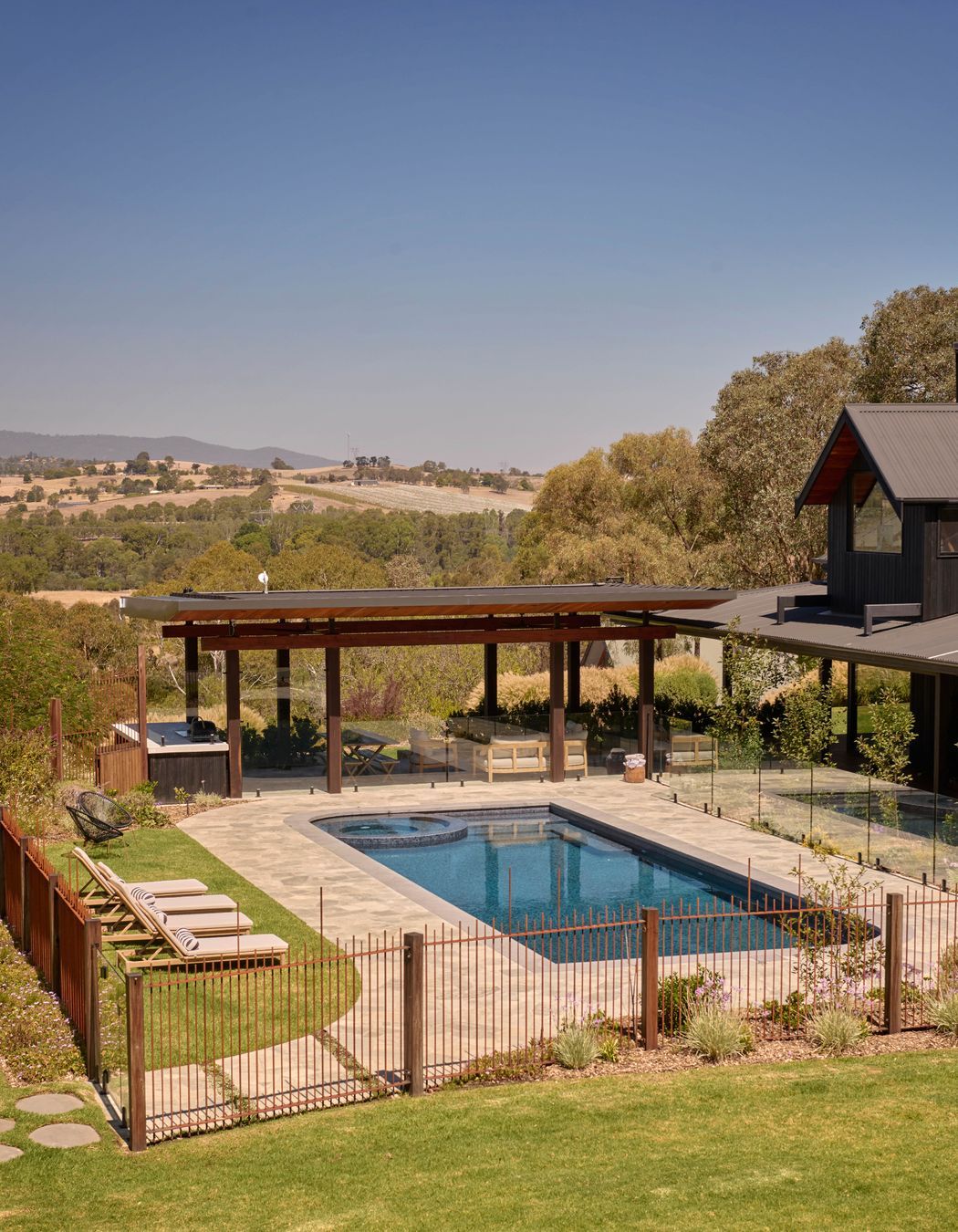 Endicott paving by Eco Outdoor around pool. Custom concrete barbecue area bench with charred timber cladding from Eco Timber Group. Sun loungers from Temple & Webster. The property looks out to Croydon and Lilydale in the distance. Pool designed with Living Landscapes Design and constructed by Saltwater Pools.