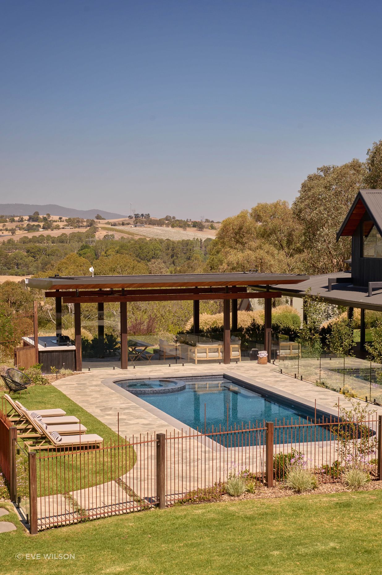 Endicott paving by Eco Outdoor around pool. Custom concrete barbecue area bench with charred timber cladding from Eco Timber Group. Sun loungers from Temple & Webster. The property looks out to Croydon and Lilydale in the distance. Pool designed with Living Landscapes Design and constructed by Saltwater Pools.