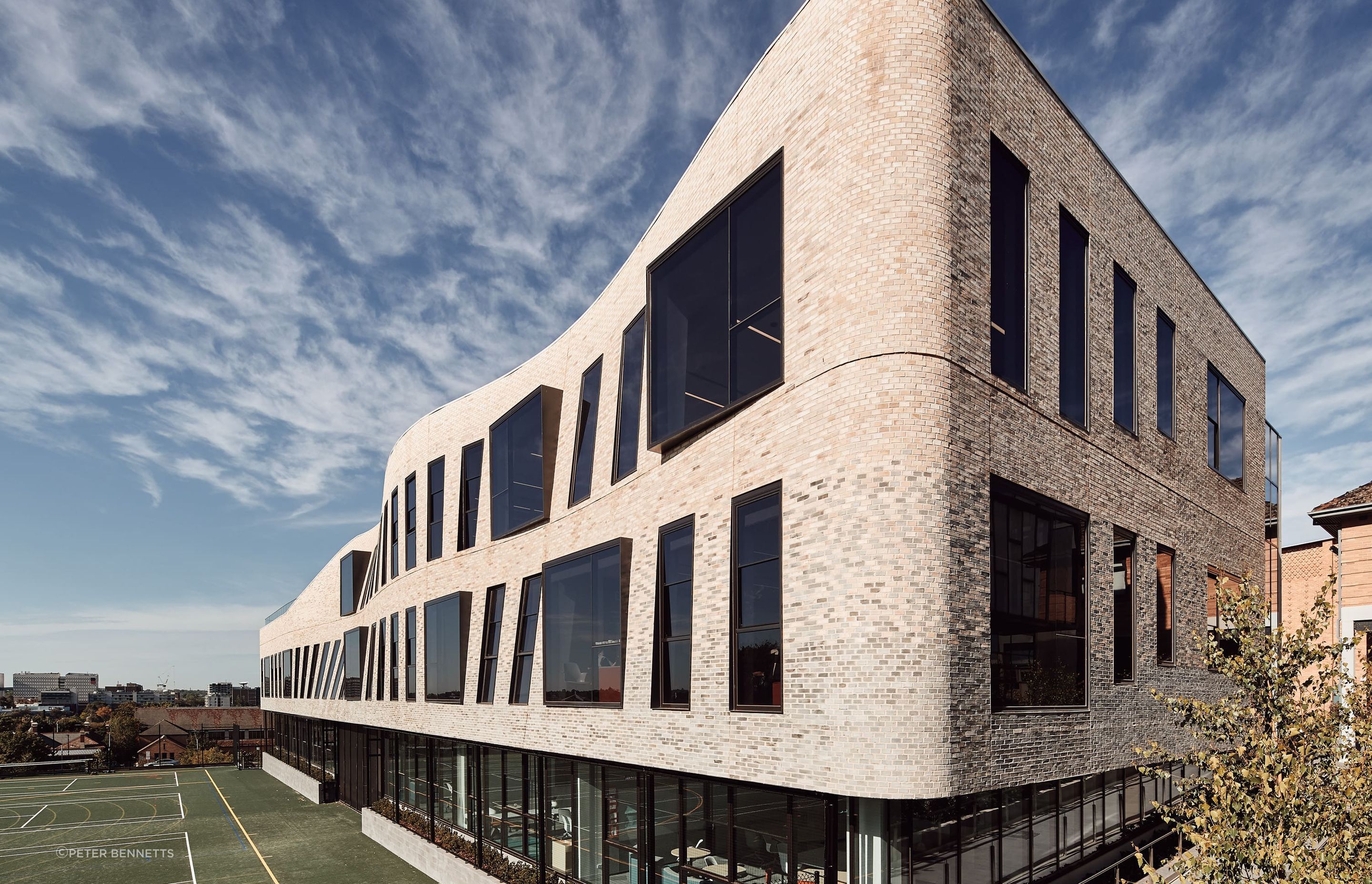 This textured facade of Petersen bricks forms a curved veil