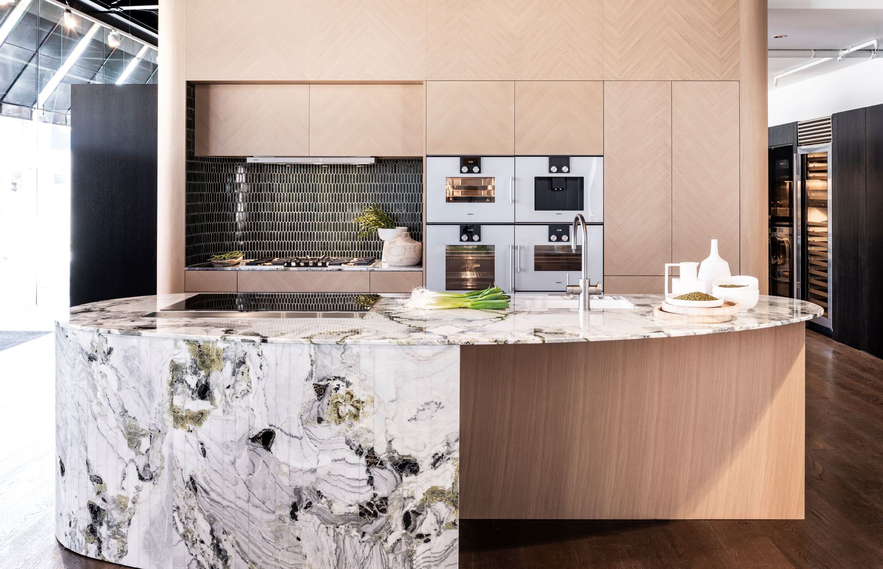 Gaggenau appliances shown in a beautiful herringbone oak display featuring khaki and emerald hues. Design by Armstrong Interiors.