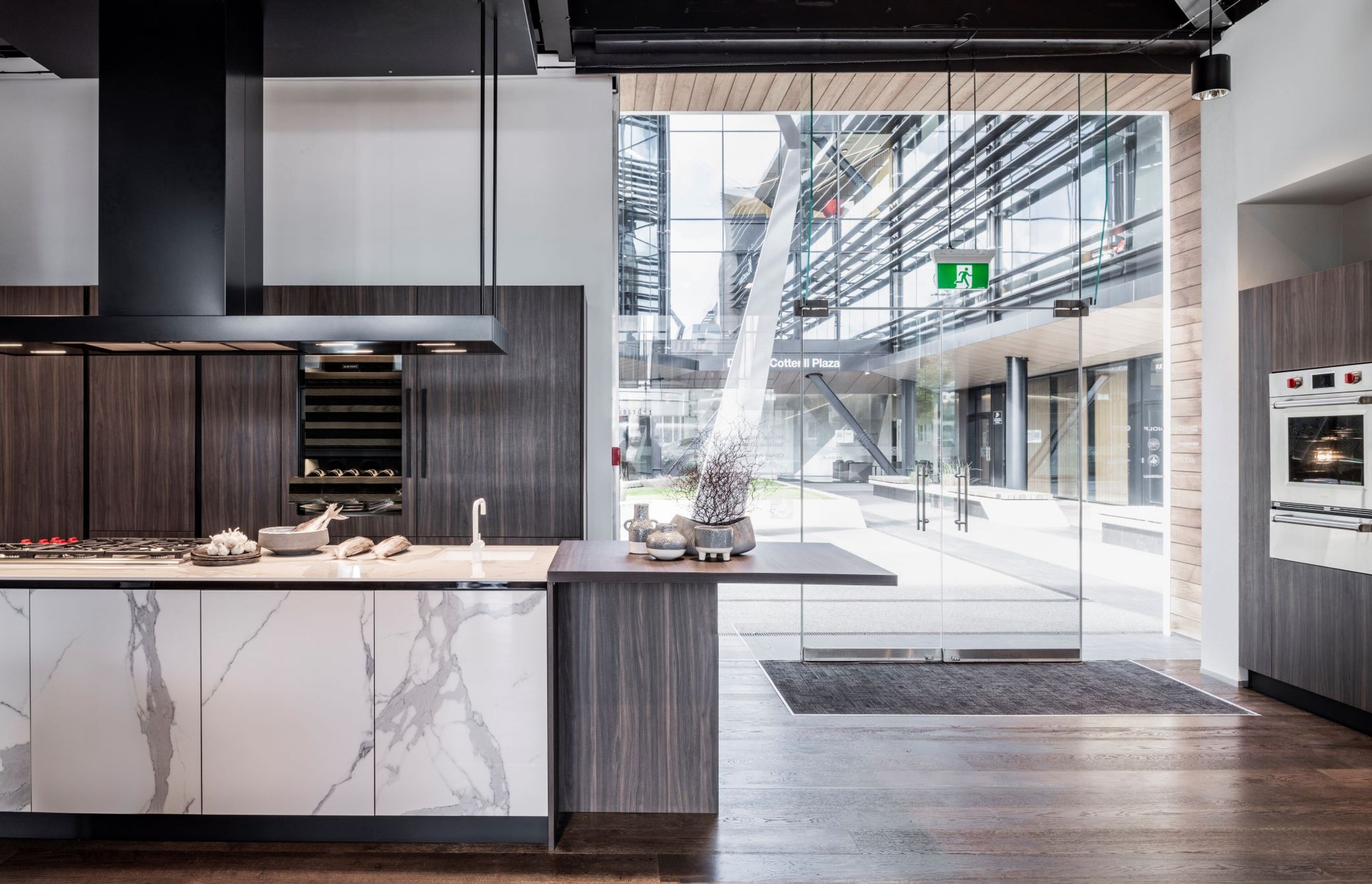 A Qasair custom rangehood hangs over a classic marble island. Sub-Zero and Wolf appliances are shown in this display by Unico.