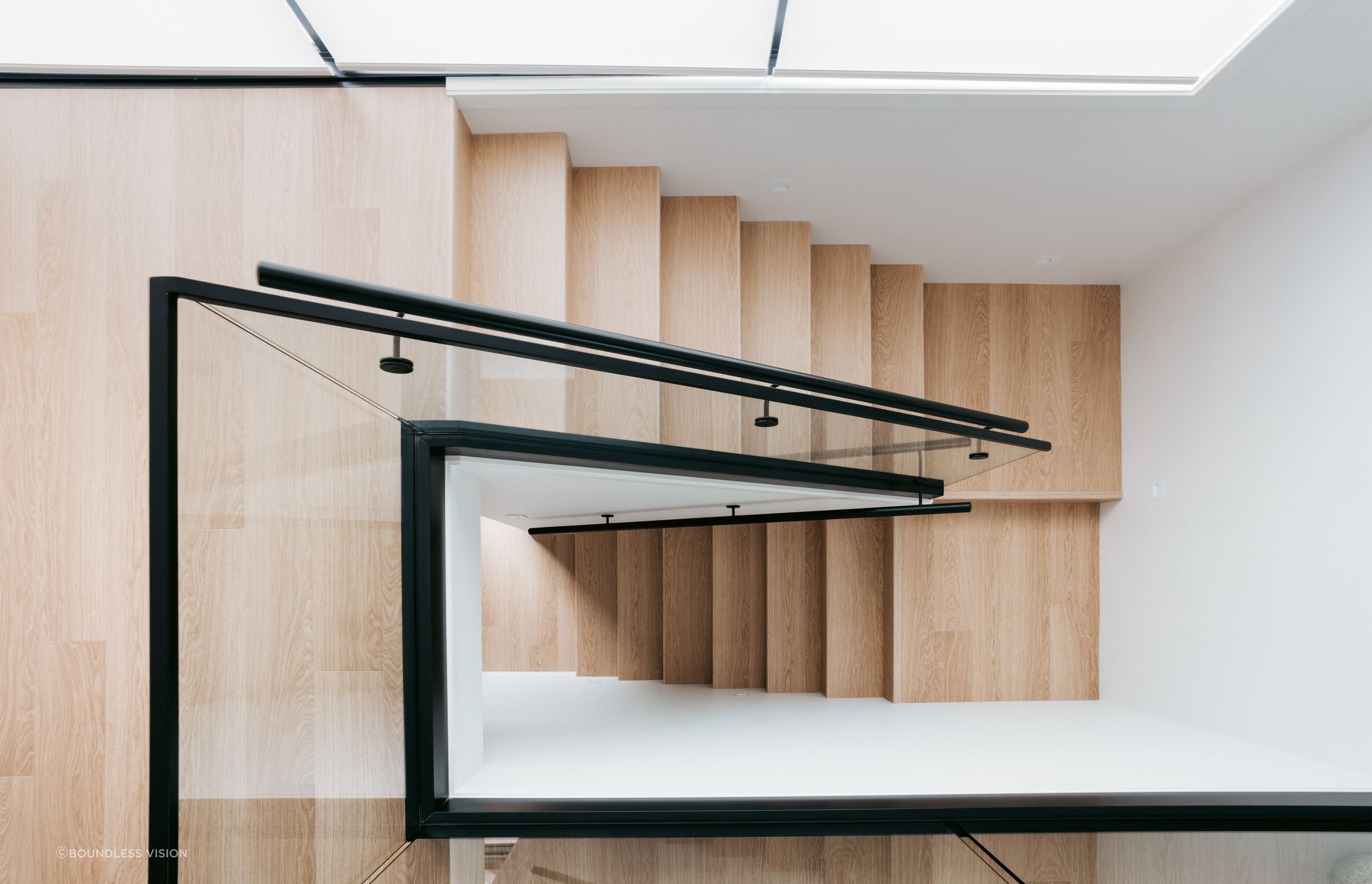 A beautifully crafted timber staircase sits below a soaring void.