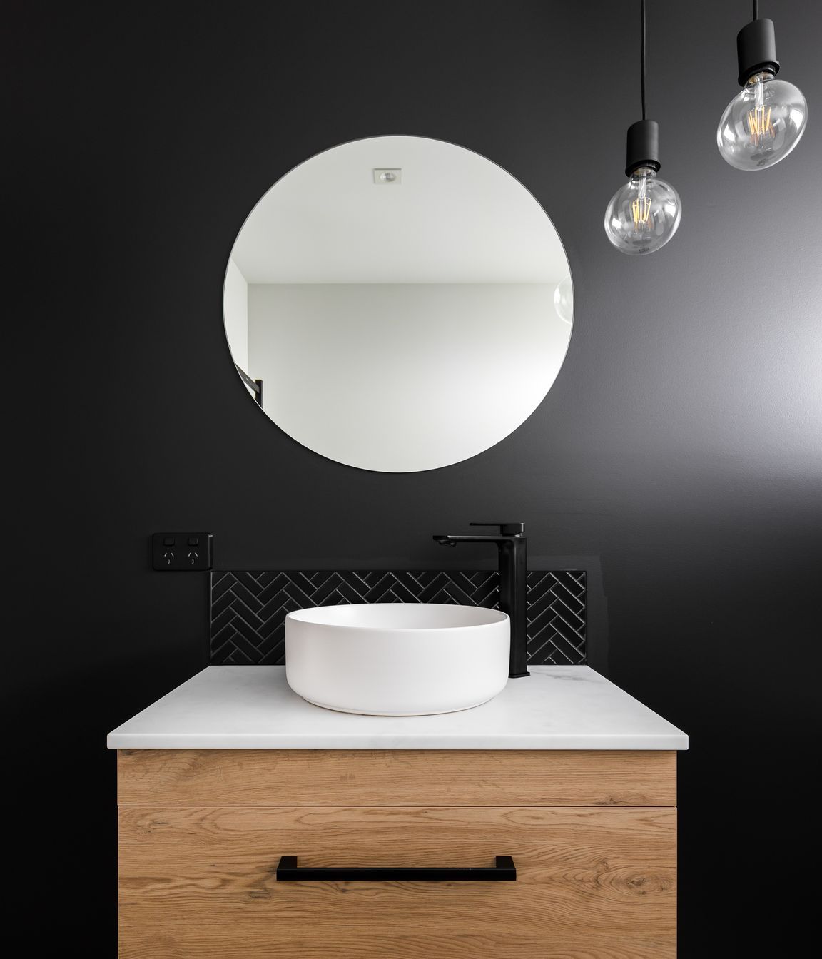 The main bathroom mimics the home's exterior with a dark feature wall.