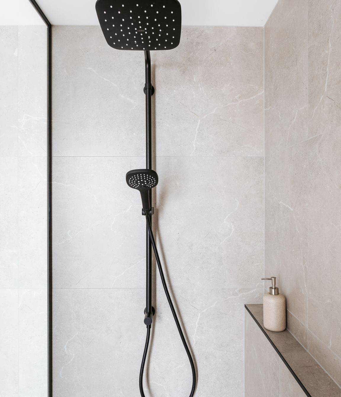 Black fixtures contrast against the stone tiling.