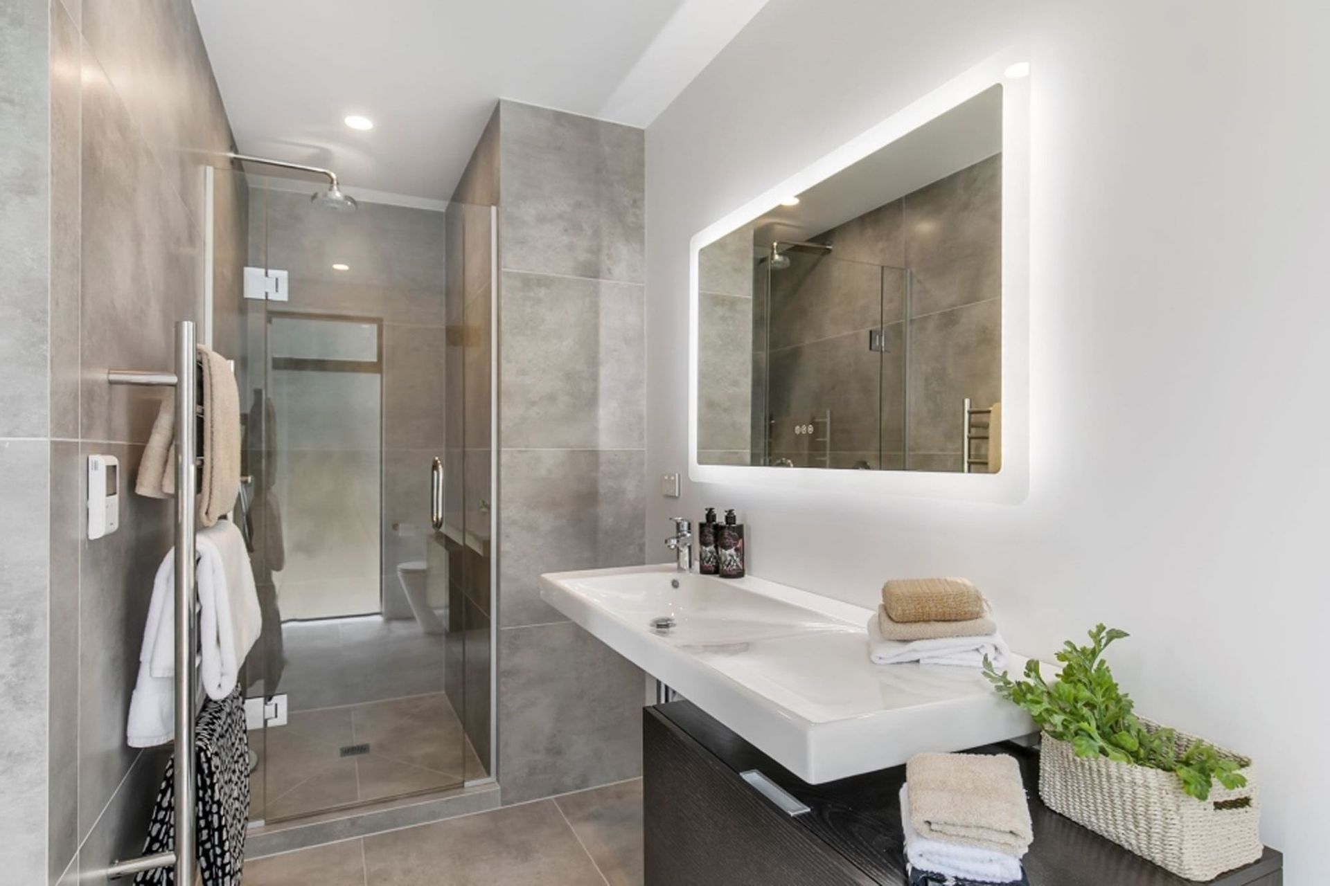 This en suite bathroom features a similar palette to the rest of the house but it has been softened through the additional of large-format tiles in a muted hue.