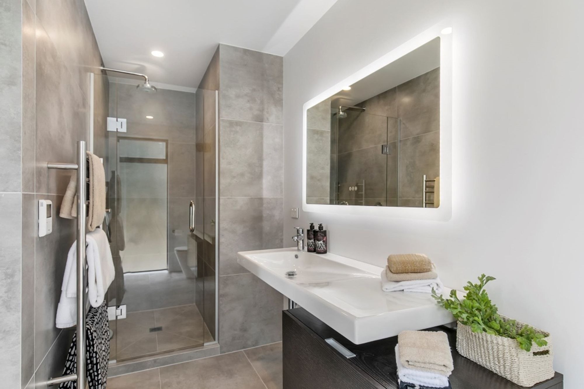 This en suite bathroom features a similar palette to the rest of the house but it has been softened through the additional of large-format tiles in a muted hue.