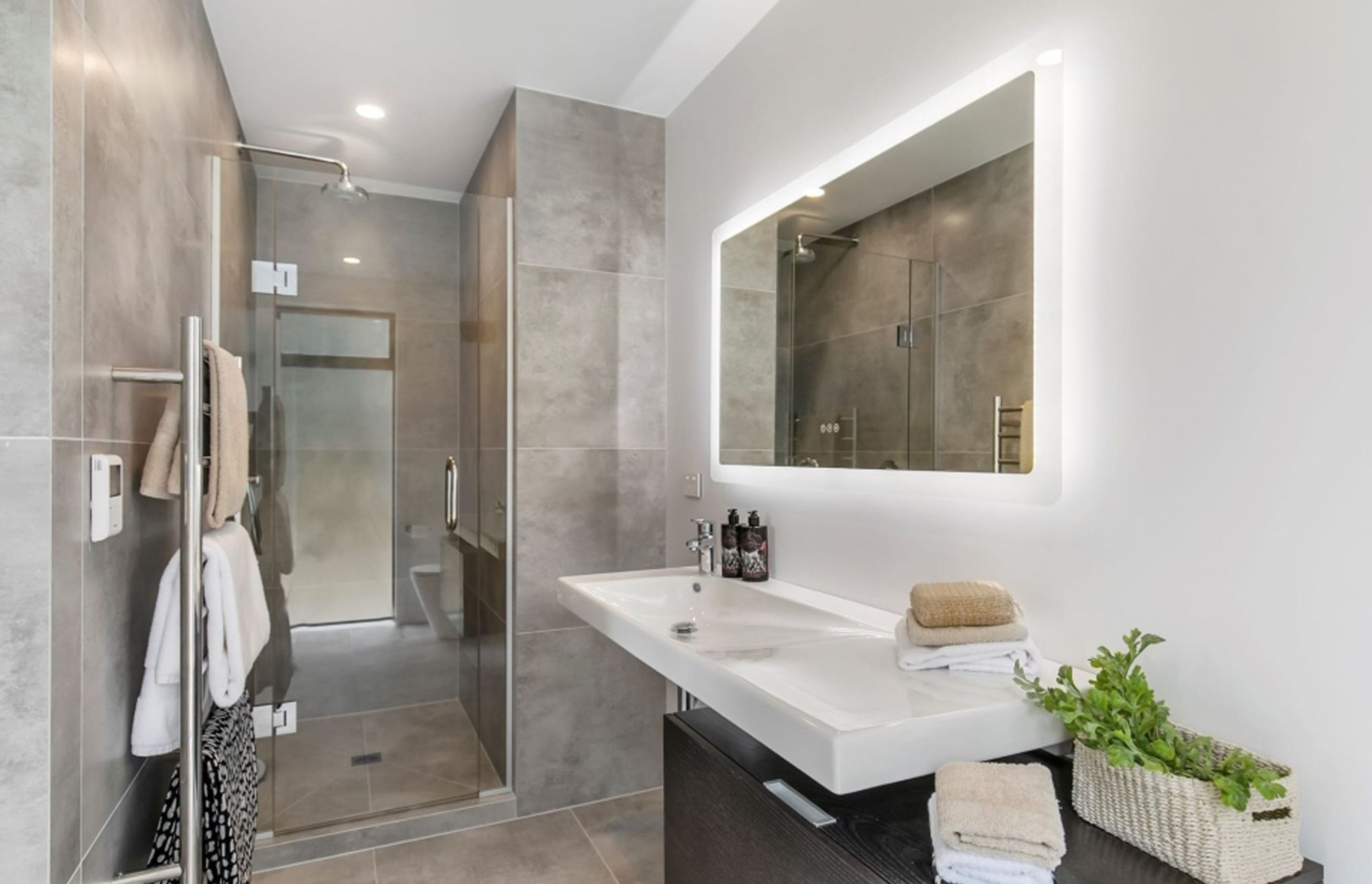 This en suite bathroom features a similar palette to the rest of the house but it has been softened through the additional of large-format tiles in a muted hue.