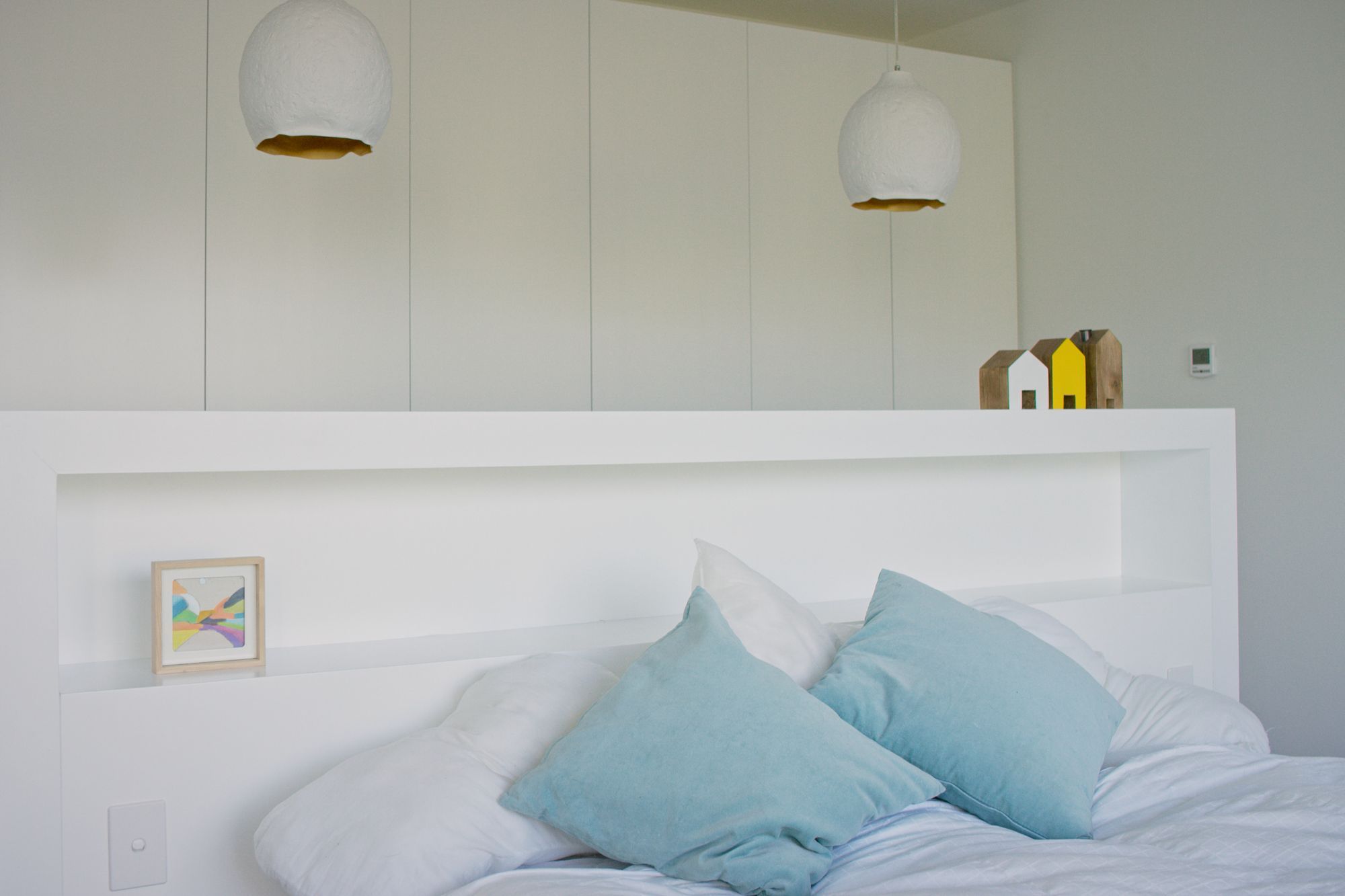 The built-in headboard provides simple storage and acts as a room divider between the bed and the wardrobes.
