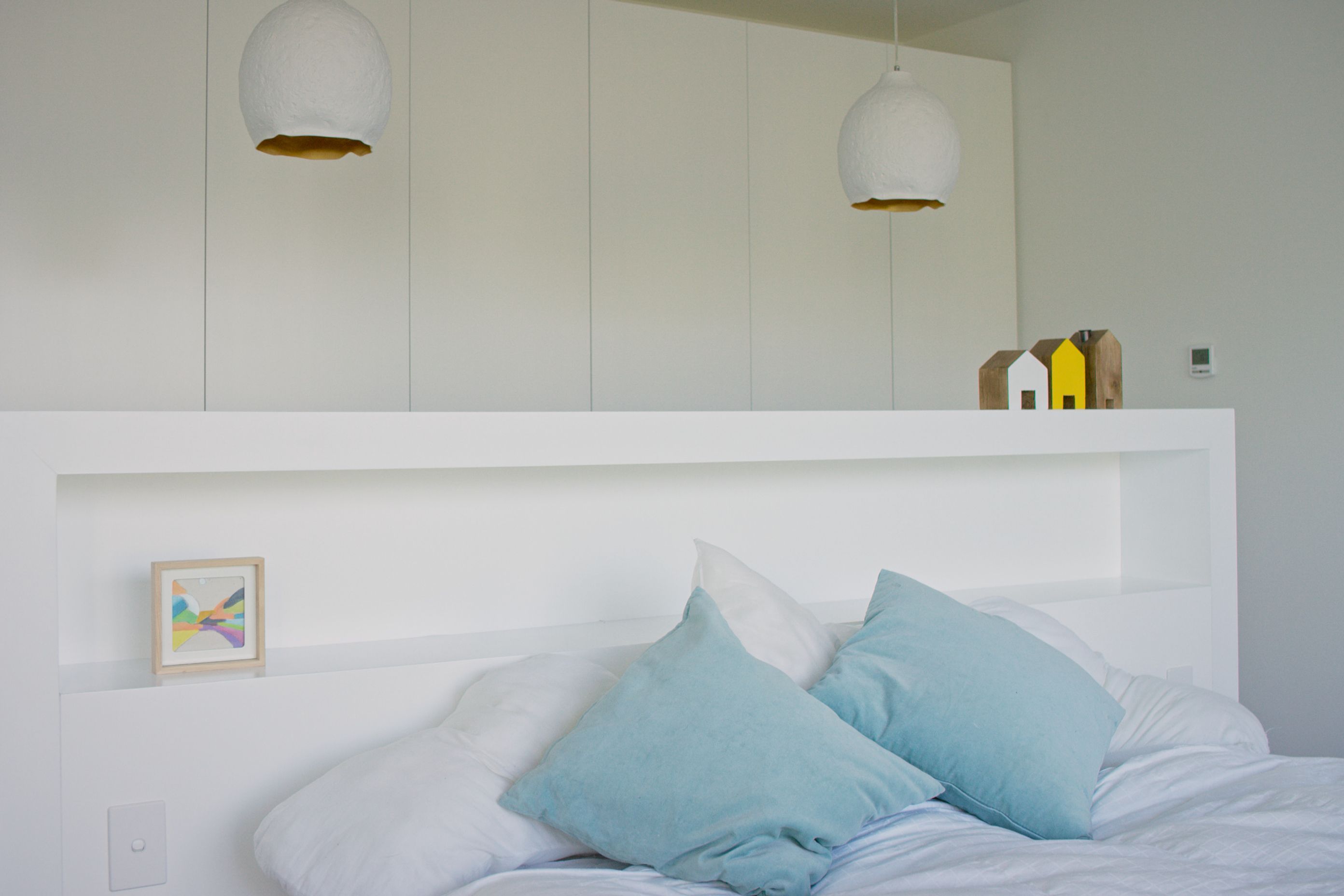 The built-in headboard provides simple storage and acts as a room divider between the bed and the wardrobes.