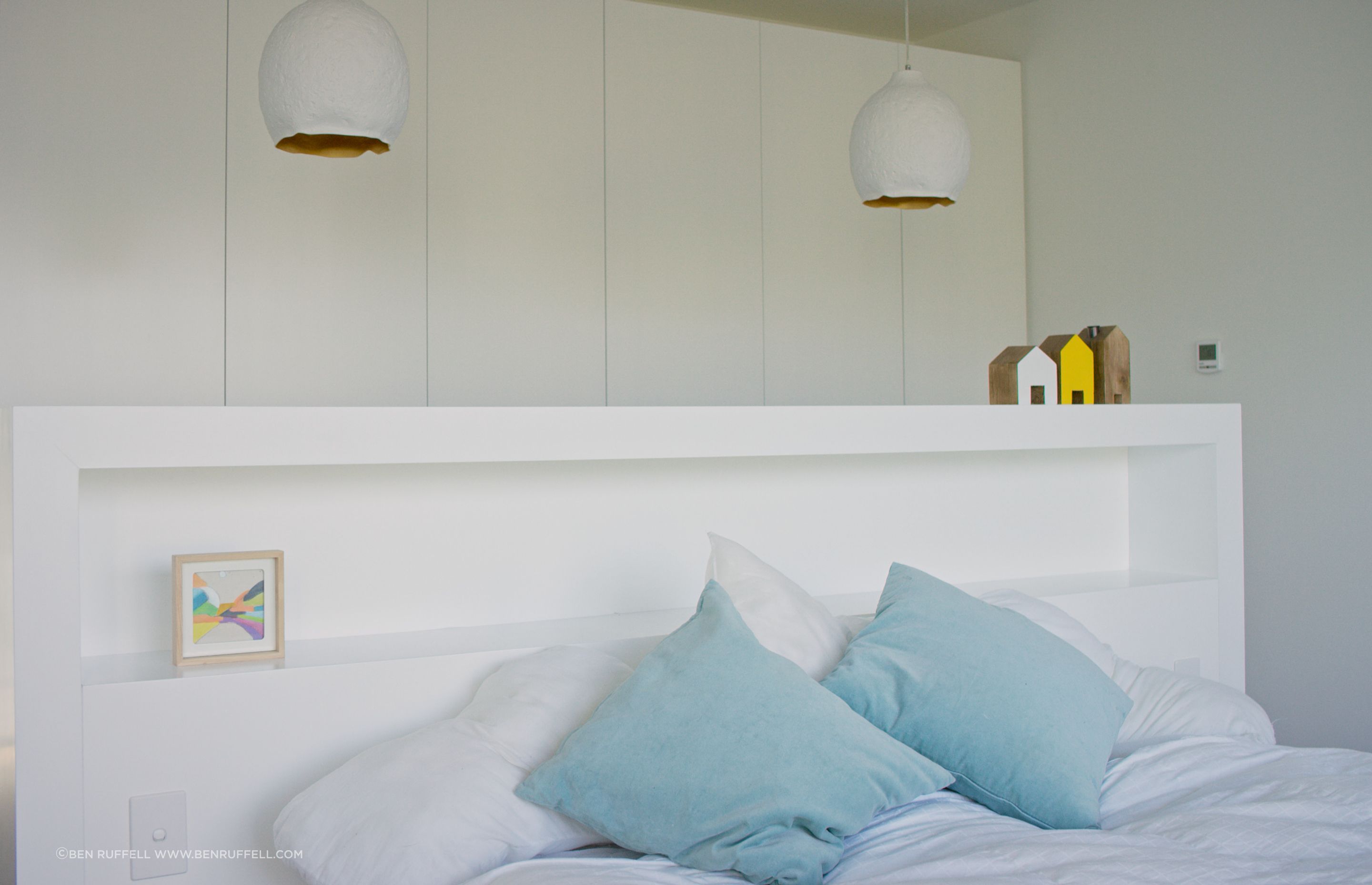 The built-in headboard provides simple storage and acts as a room divider between the bed and the wardrobes.