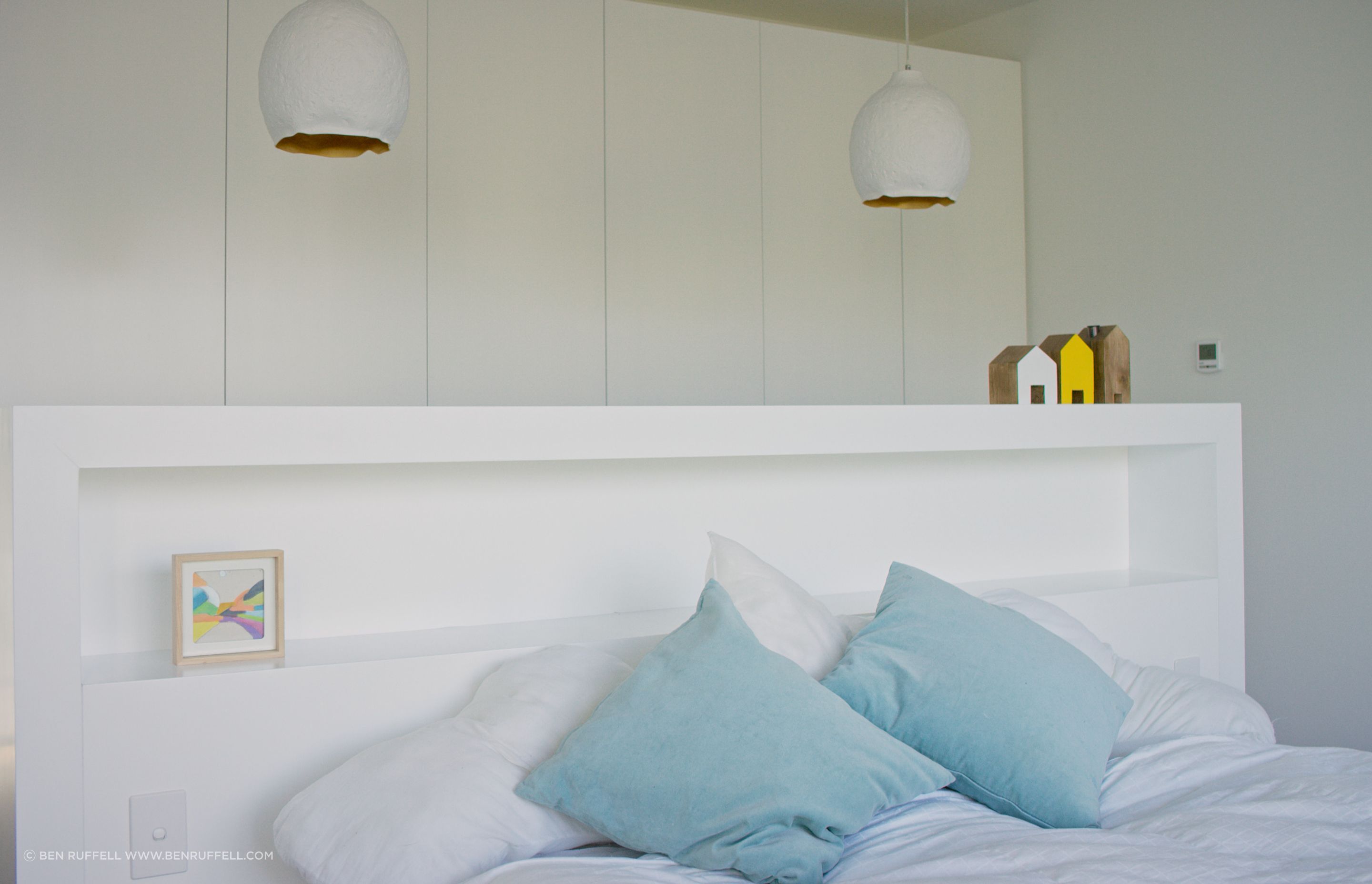 The built-in headboard provides simple storage and acts as a room divider between the bed and the wardrobes.