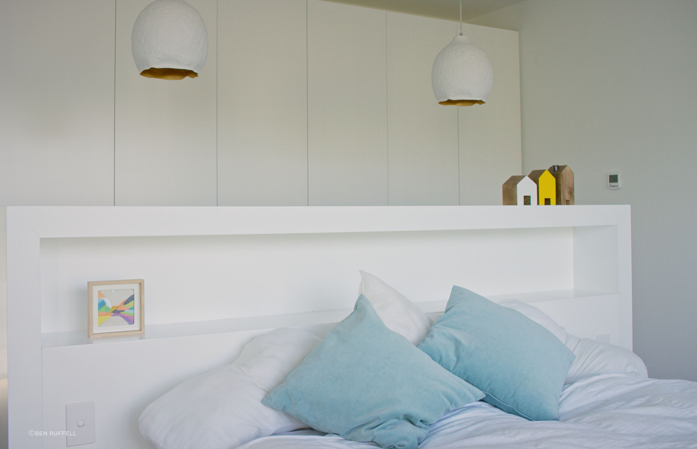 The built-in headboard provides simple storage and acts as a room divider between the bed and the wardrobes.