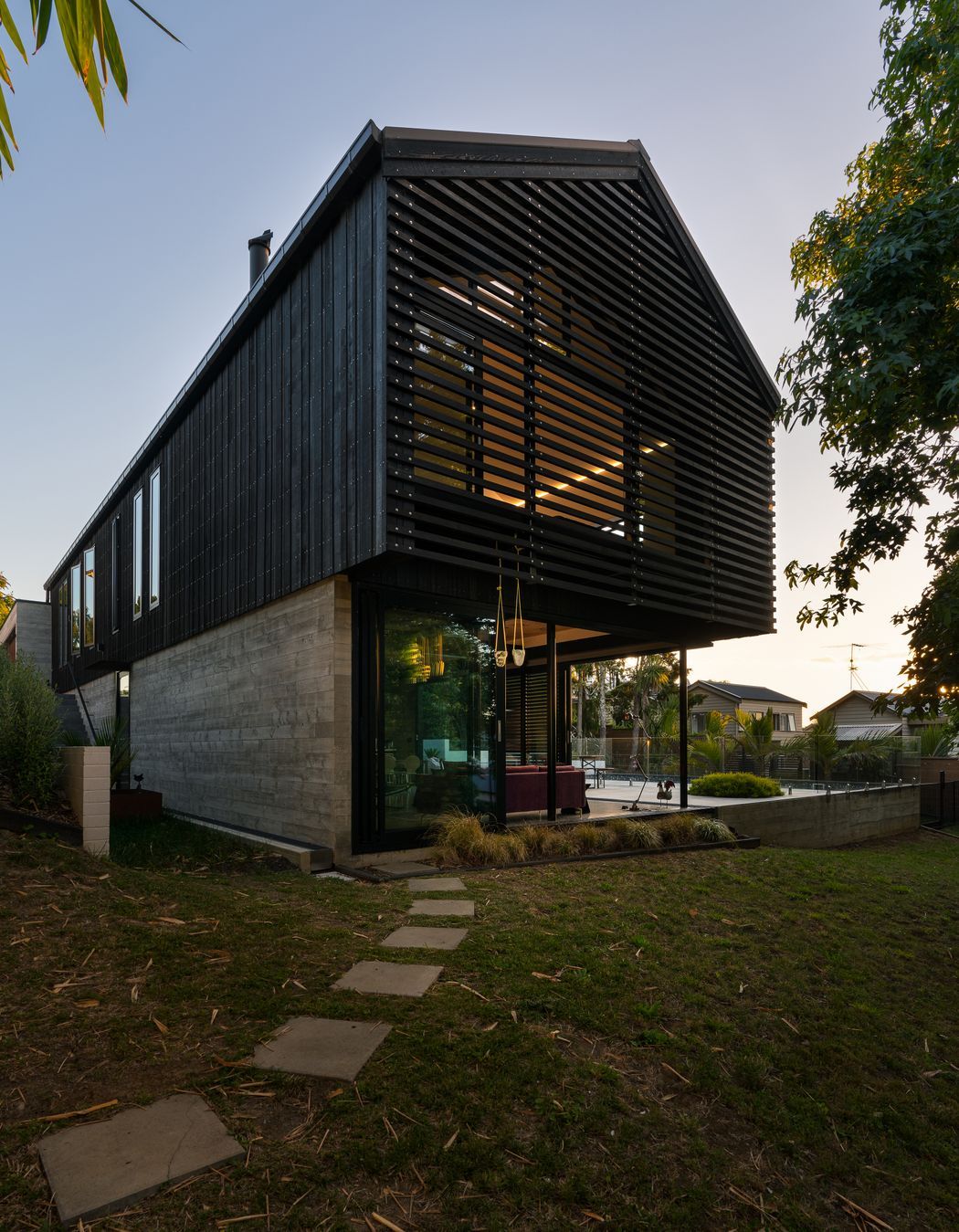 The family home of architect Clive Chapman of Pacific Environments Architects in Auckland. The gable roof, the vertical siding, the small windows and the strength of the concrete and corten steel are all references to the industrial shed feel that Clive wanted.