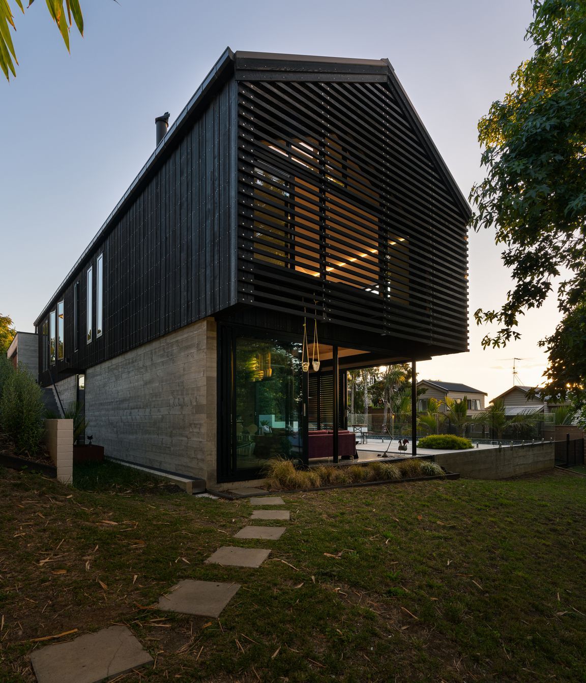 The family home of architect Clive Chapman of Pacific Environments Architects in Auckland. The gable roof, the vertical siding, the small windows and the strength of the concrete and corten steel are all references to the industrial shed feel that Clive wanted.