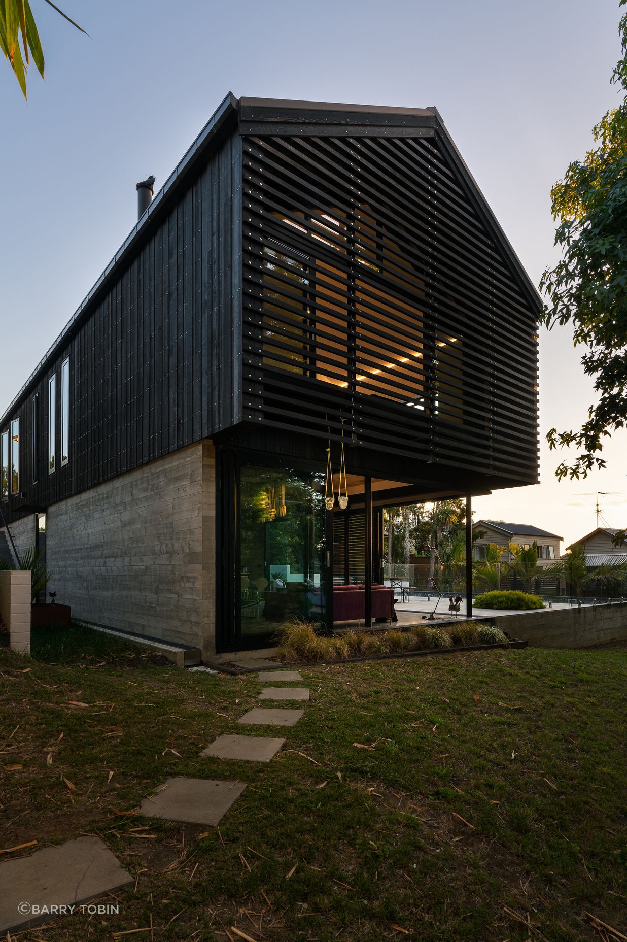 The family home of architect Clive Chapman of Pacific Environments Architects in Auckland. The gable roof, the vertical siding, the small windows and the strength of the concrete and corten steel are all references to the industrial shed feel that Clive wanted.