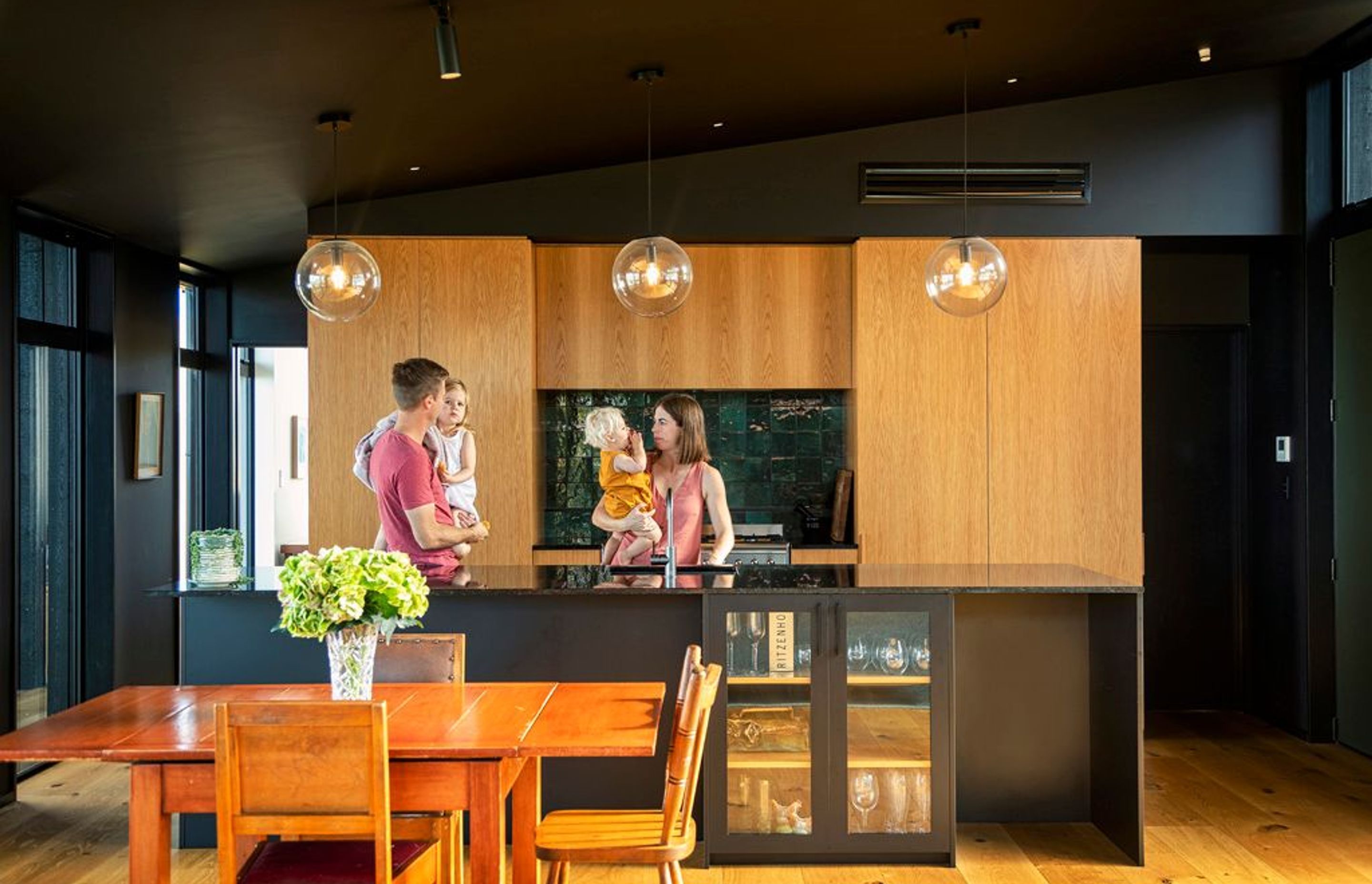 Engineered oak flooring and oak accents in the kitchen add warmth to the otherwise dark colour palette.