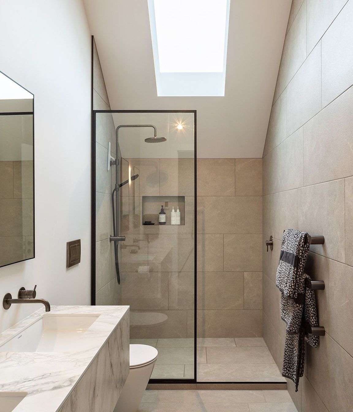 A skylight is cut into the master en suite, cleverly negating the need for a window and illuminating the natural stone palette.