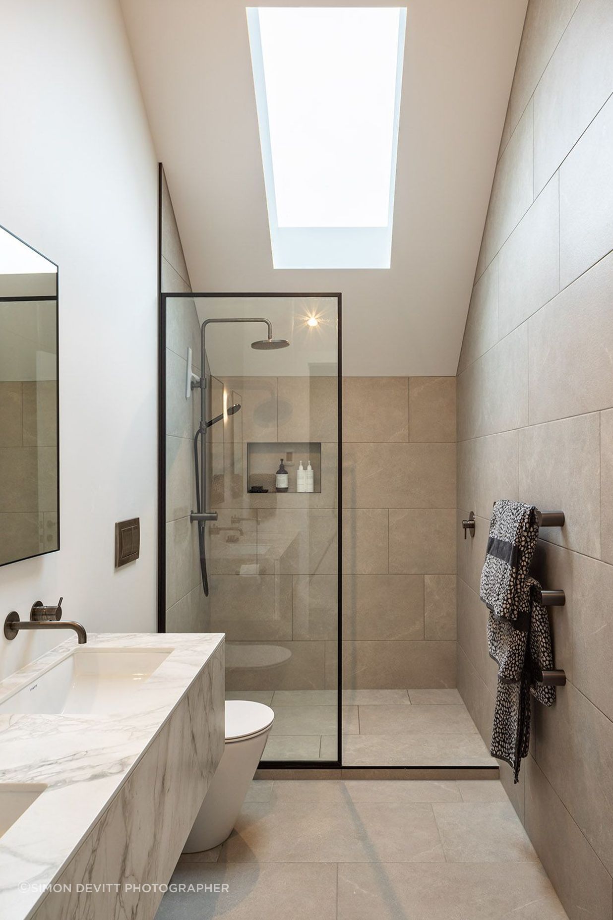 A skylight is cut into the master en suite, cleverly negating the need for a window and illuminating the natural stone palette.