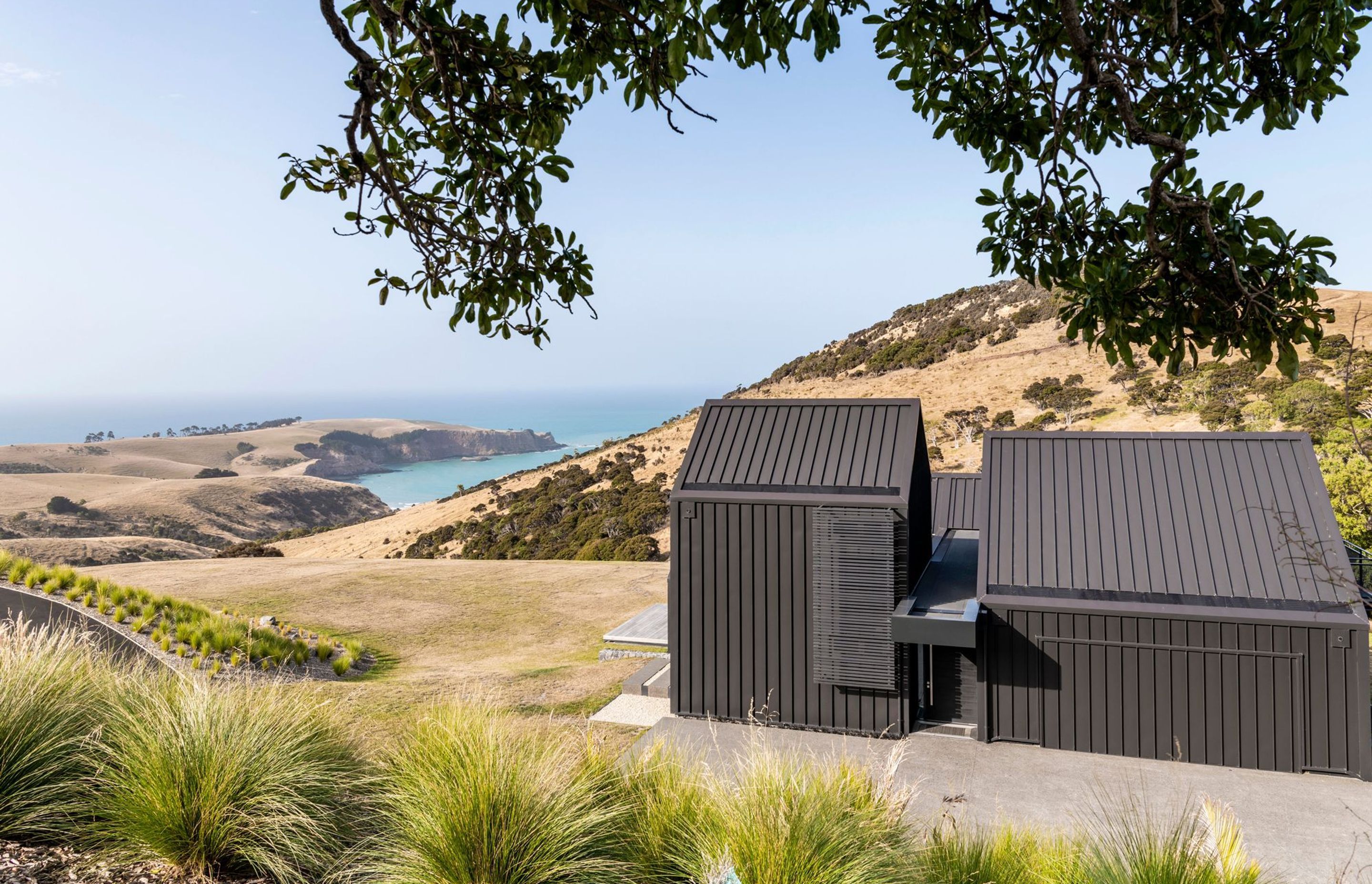 The brutalist front elevation of the entryway belies the light filled interior and ethereal views over stunning Raupo Bay.