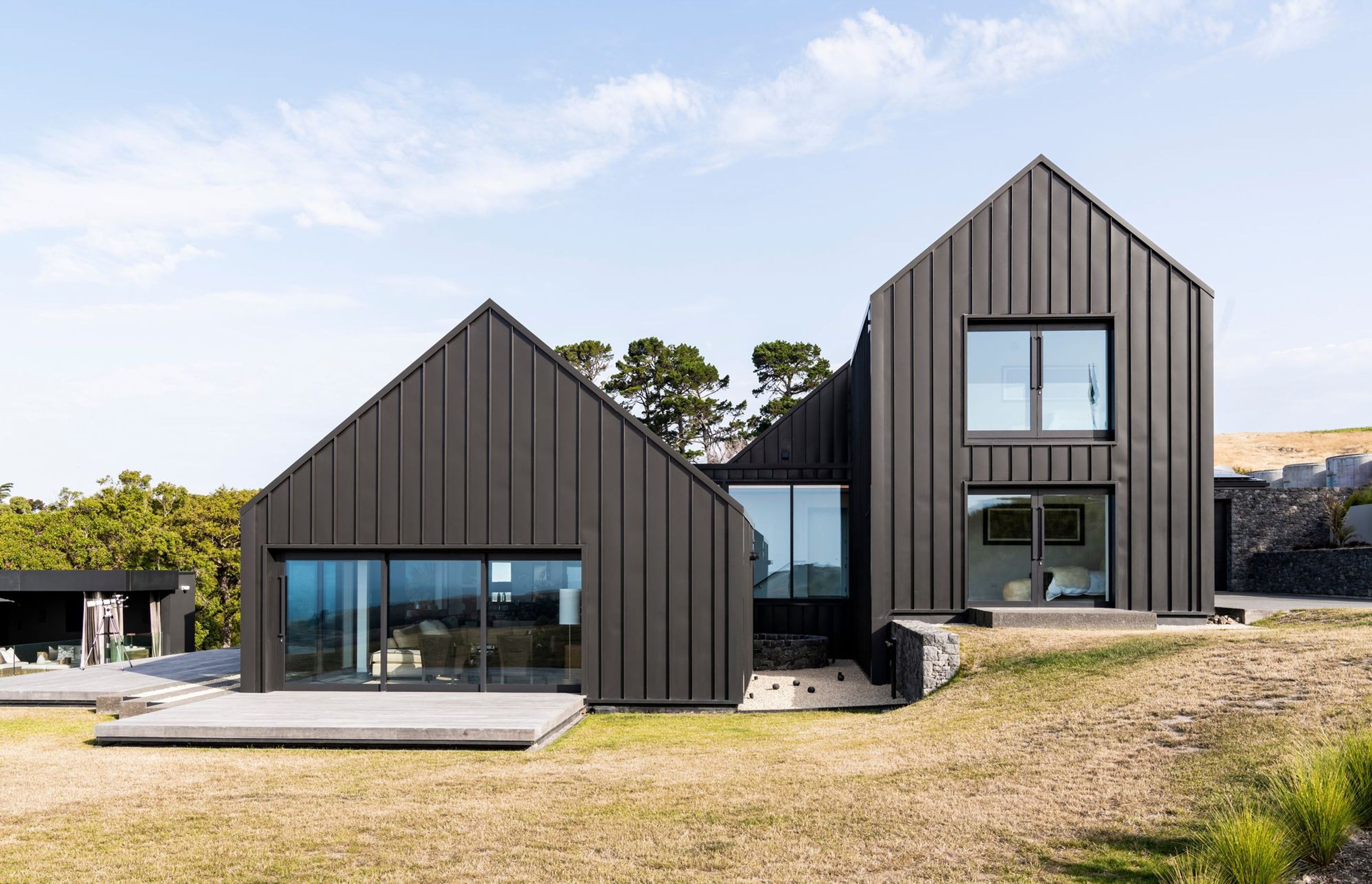 The gable form containing the living spaces steps down from the two-storey gable form containing accommodation.