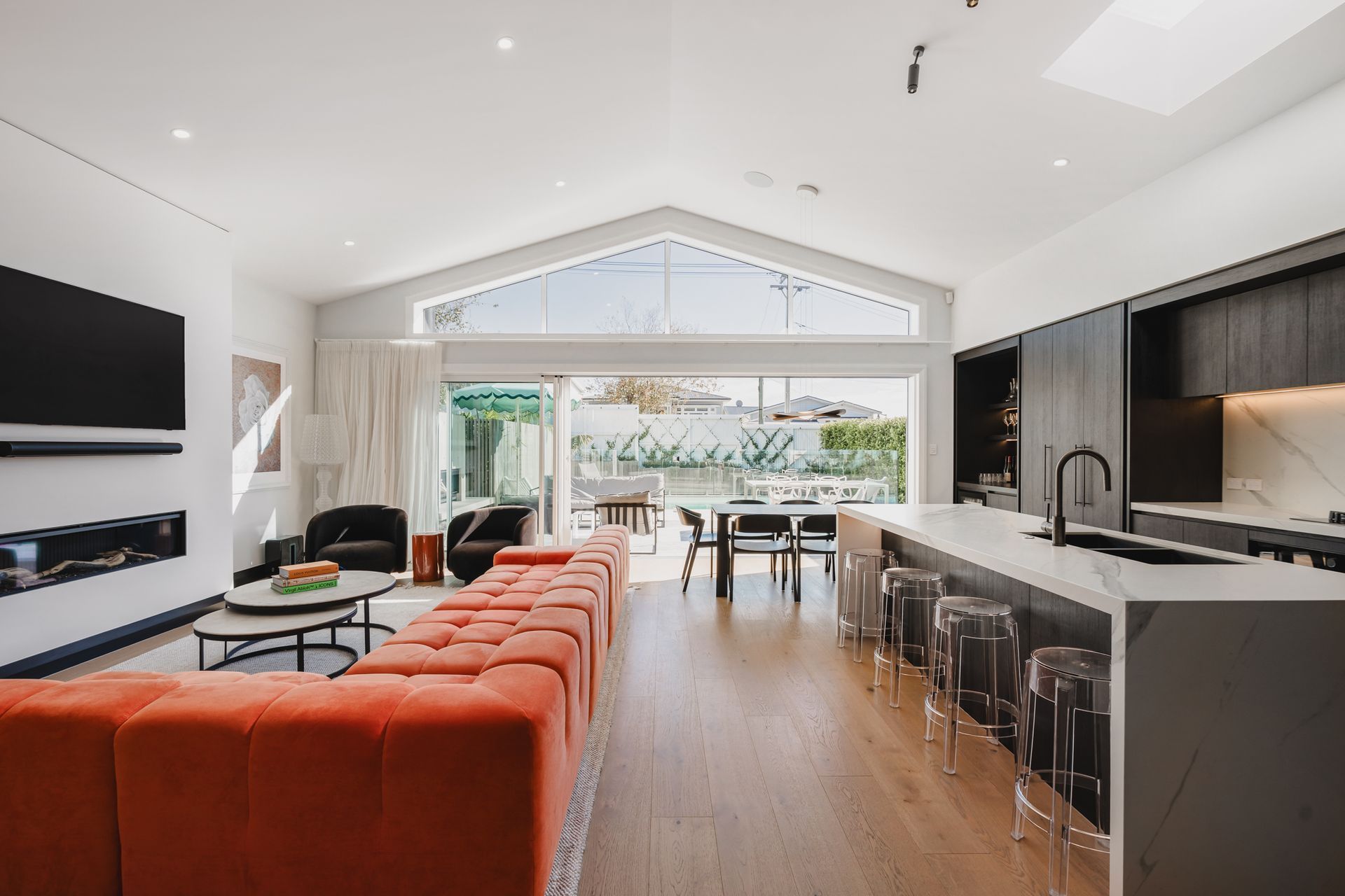 Westmere Bungalow | New-Build Residence | Internal view of open plan living, kitchen and dining room, with vaulted ceilings and gas fireplace.
